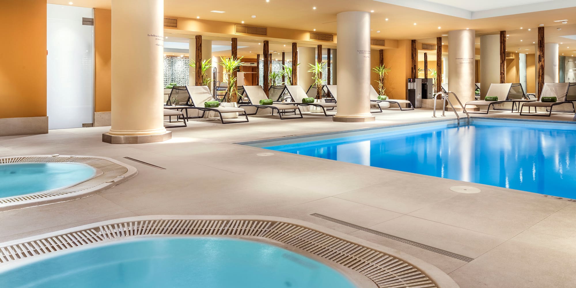 a swimming pool with a hot tub and lounge chairs