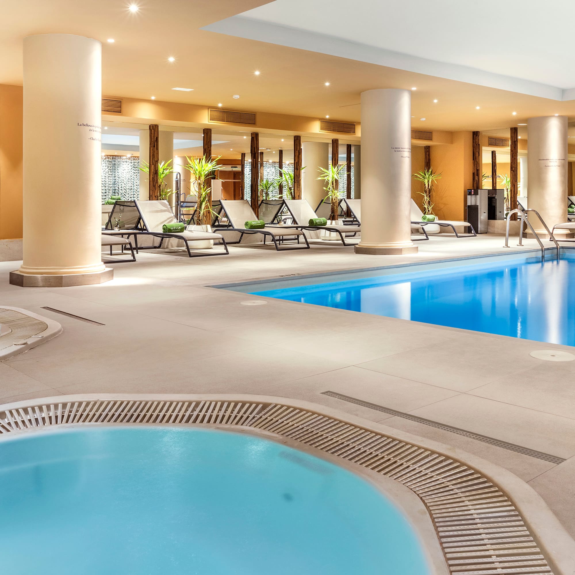 Indoor hotel spa with swimming pool, two hot tubs, and lounge chairs.