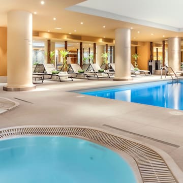 a swimming pool with a hot tub and lounge chairs