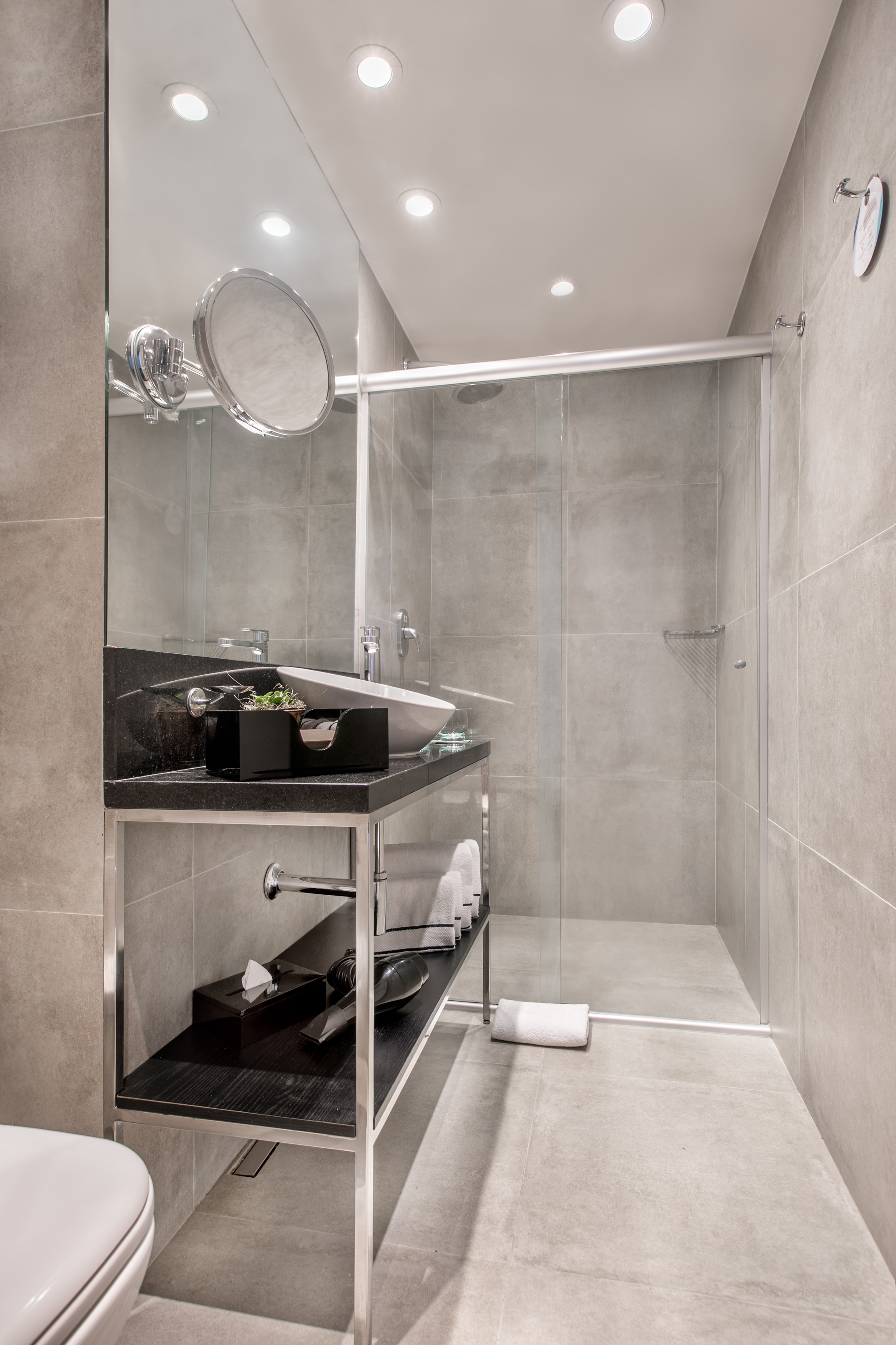 Modern gray bathroom with vessel sink vanity, large mirror, and glass shower.
