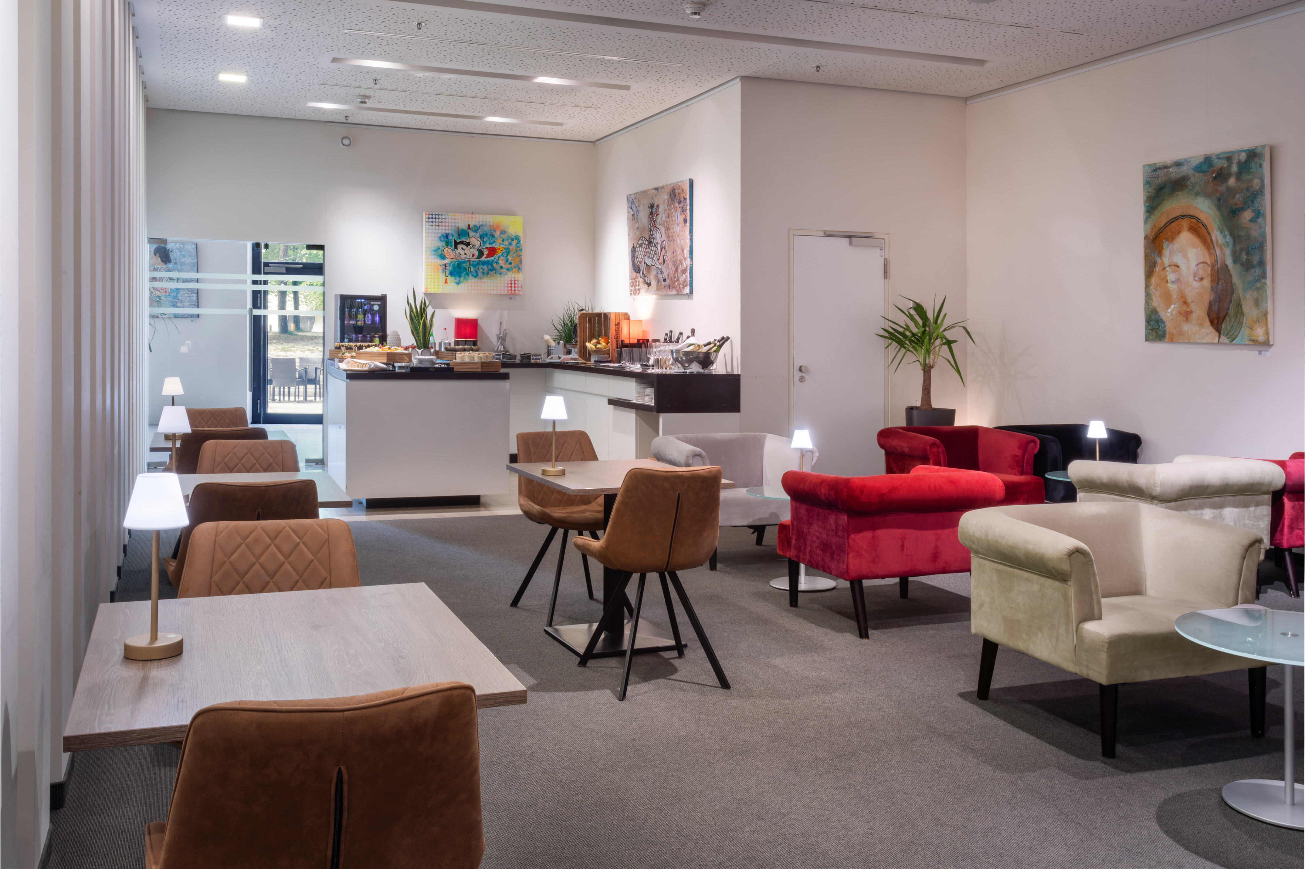 Hotel lounge with buffet, dining tables, and comfortable armchairs.