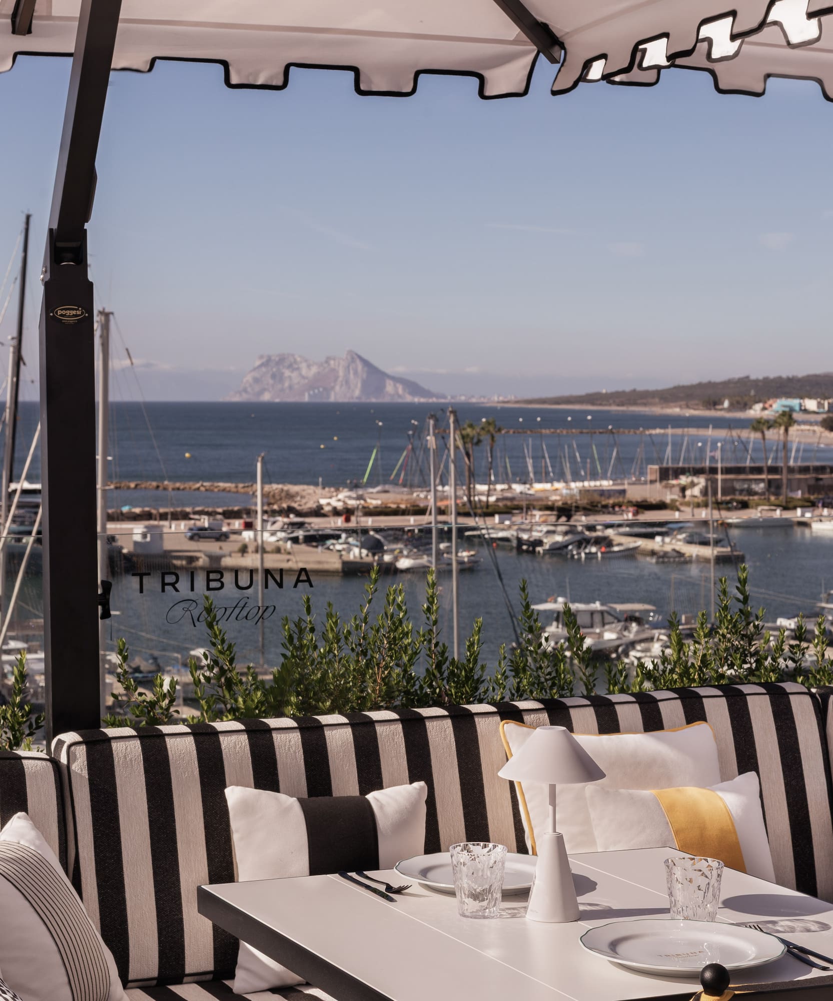 a table and chairs with a view of the water and boats in the background