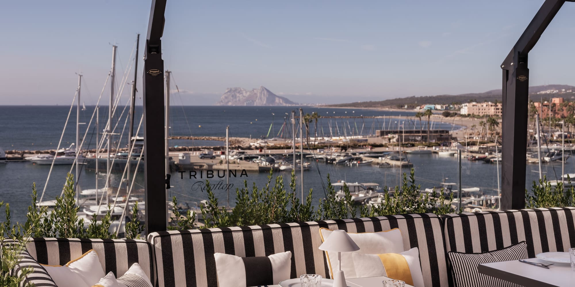 a table and chairs with a view of the water and boats in the background