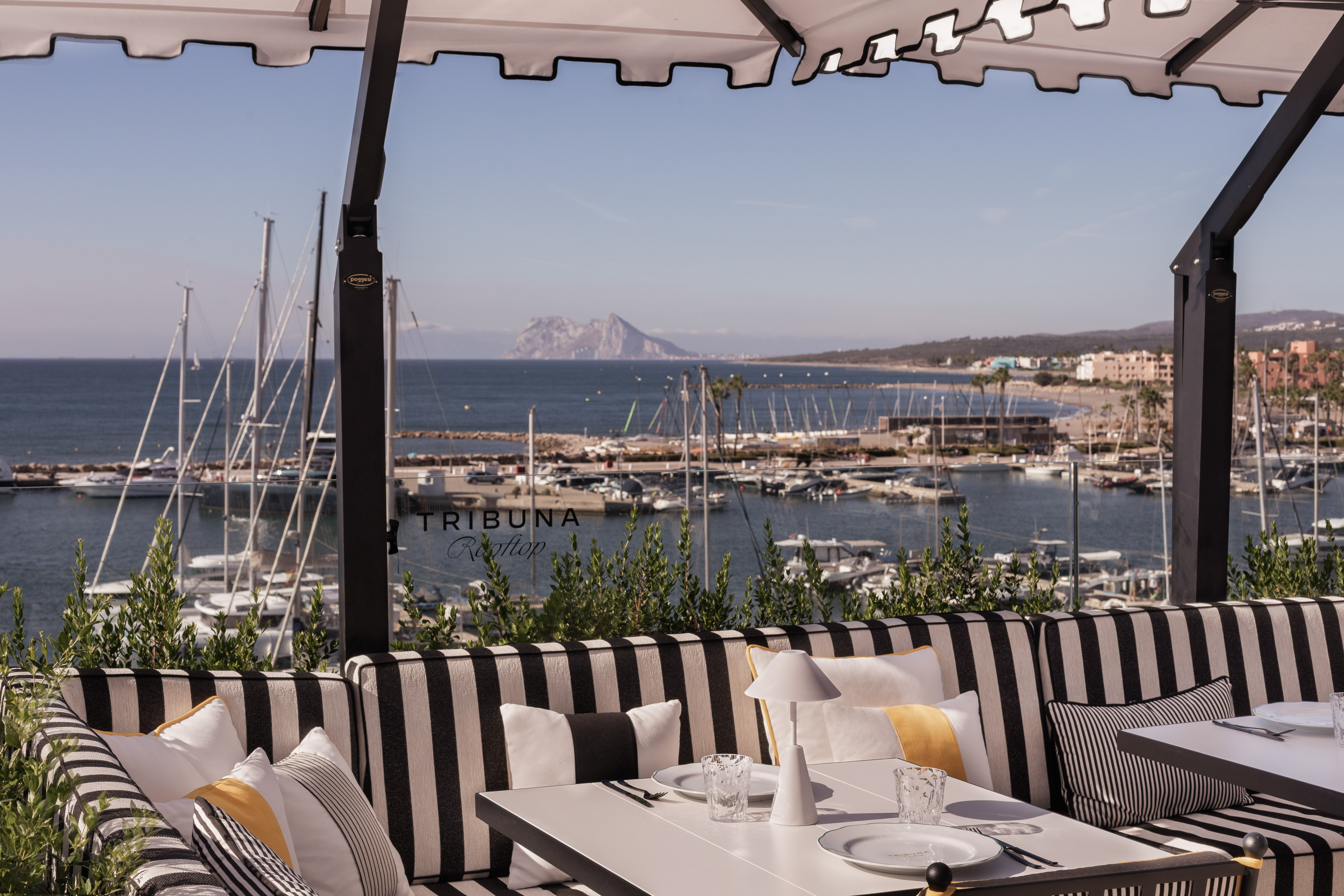 Rooftop dining with marina view, sailboats, and Rock of Gibraltar.