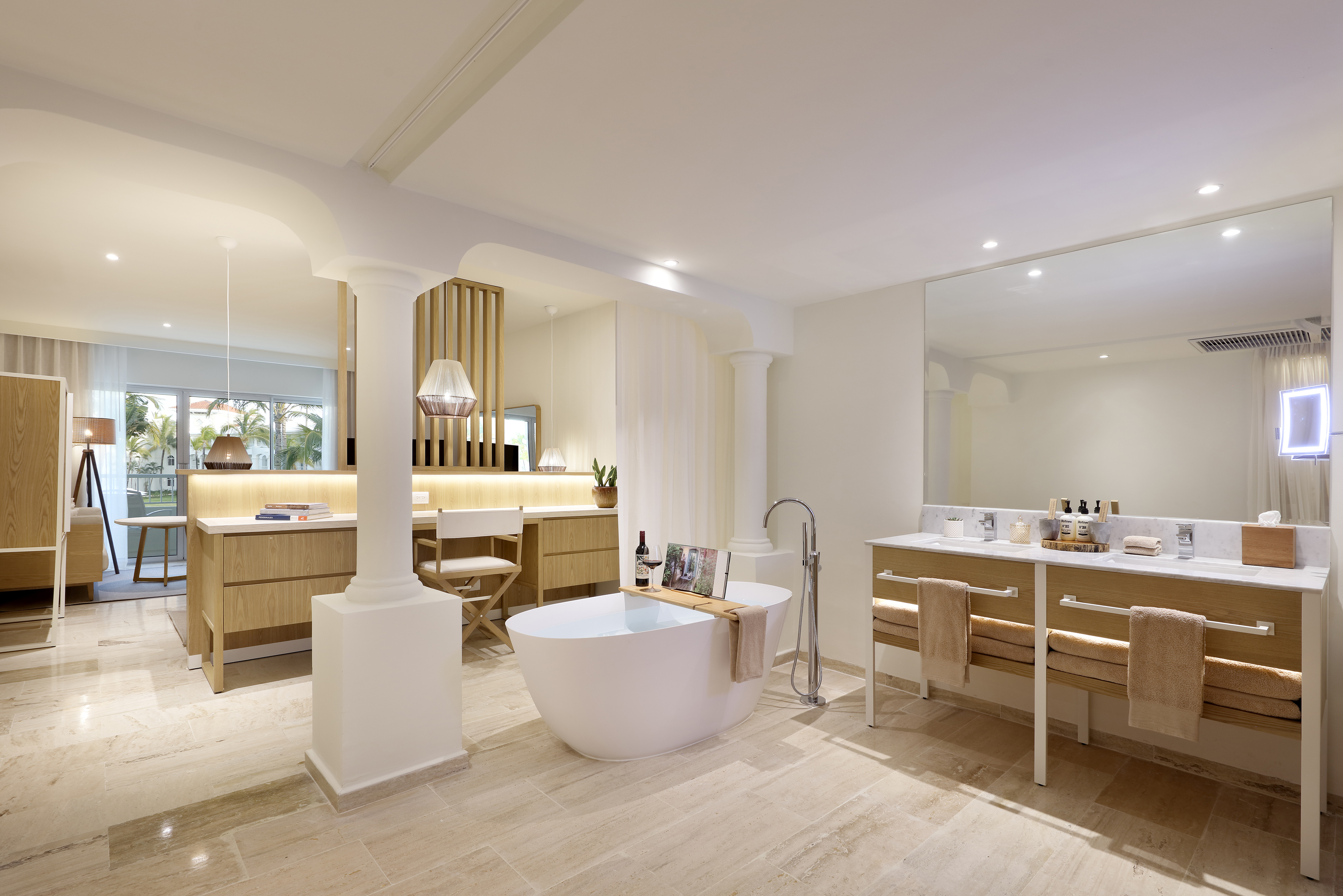 Modern luxury hotel bathroom with freestanding tub, dual vanity, and tropical view.