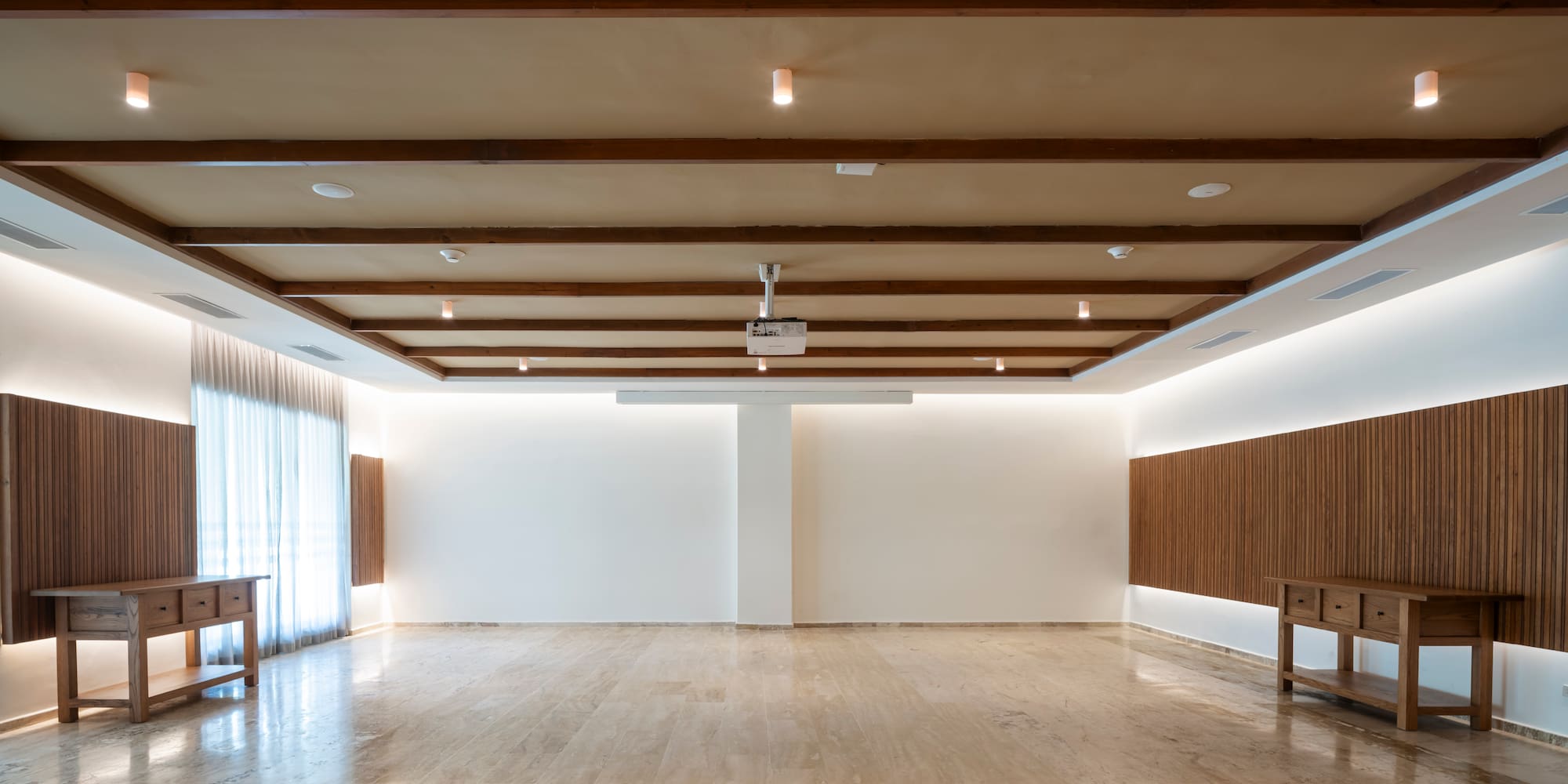 Empty modern event hall with marble floor, wood beams, and projector.