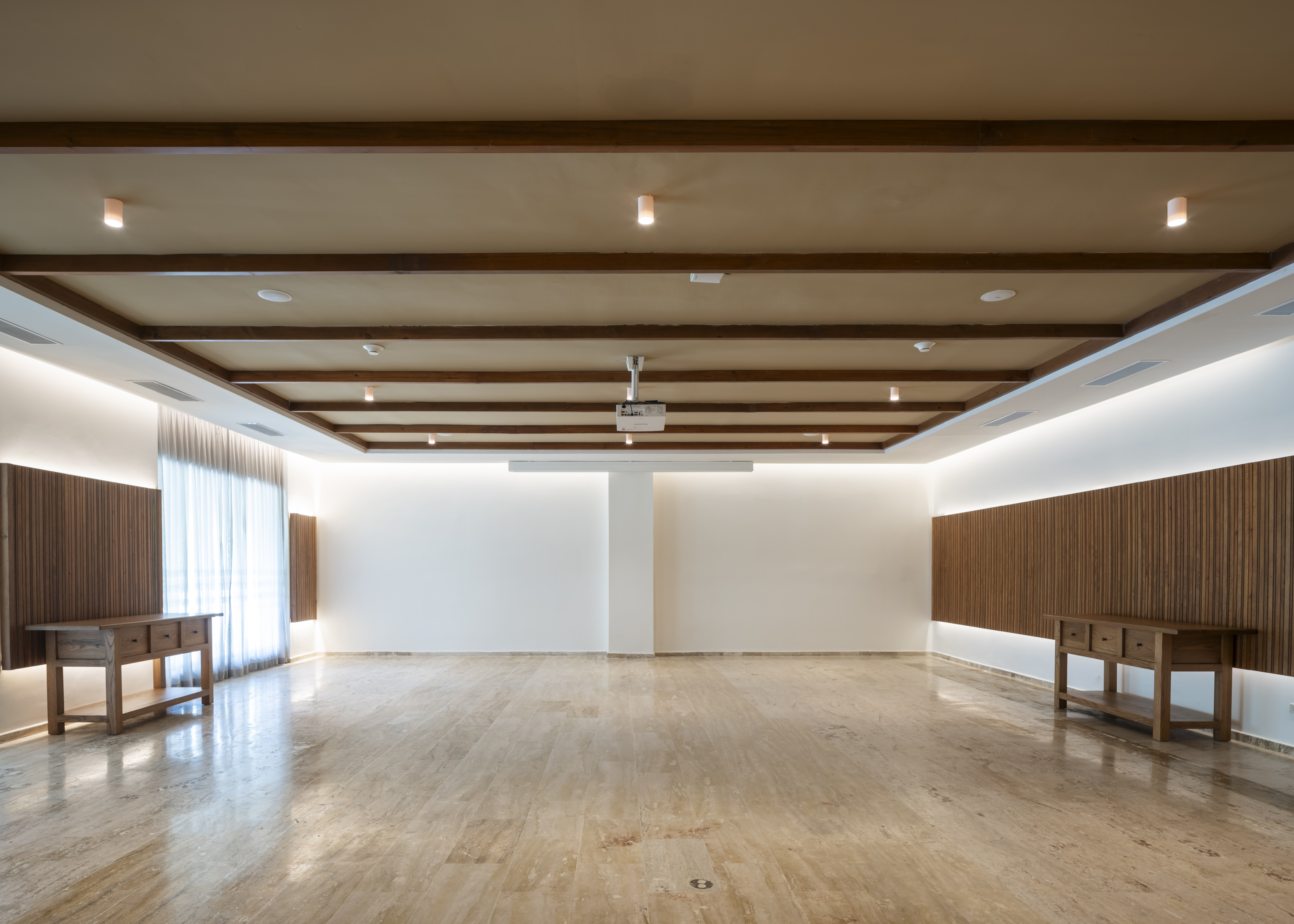 Empty modern event hall with marble floor, wood beams, and projector.