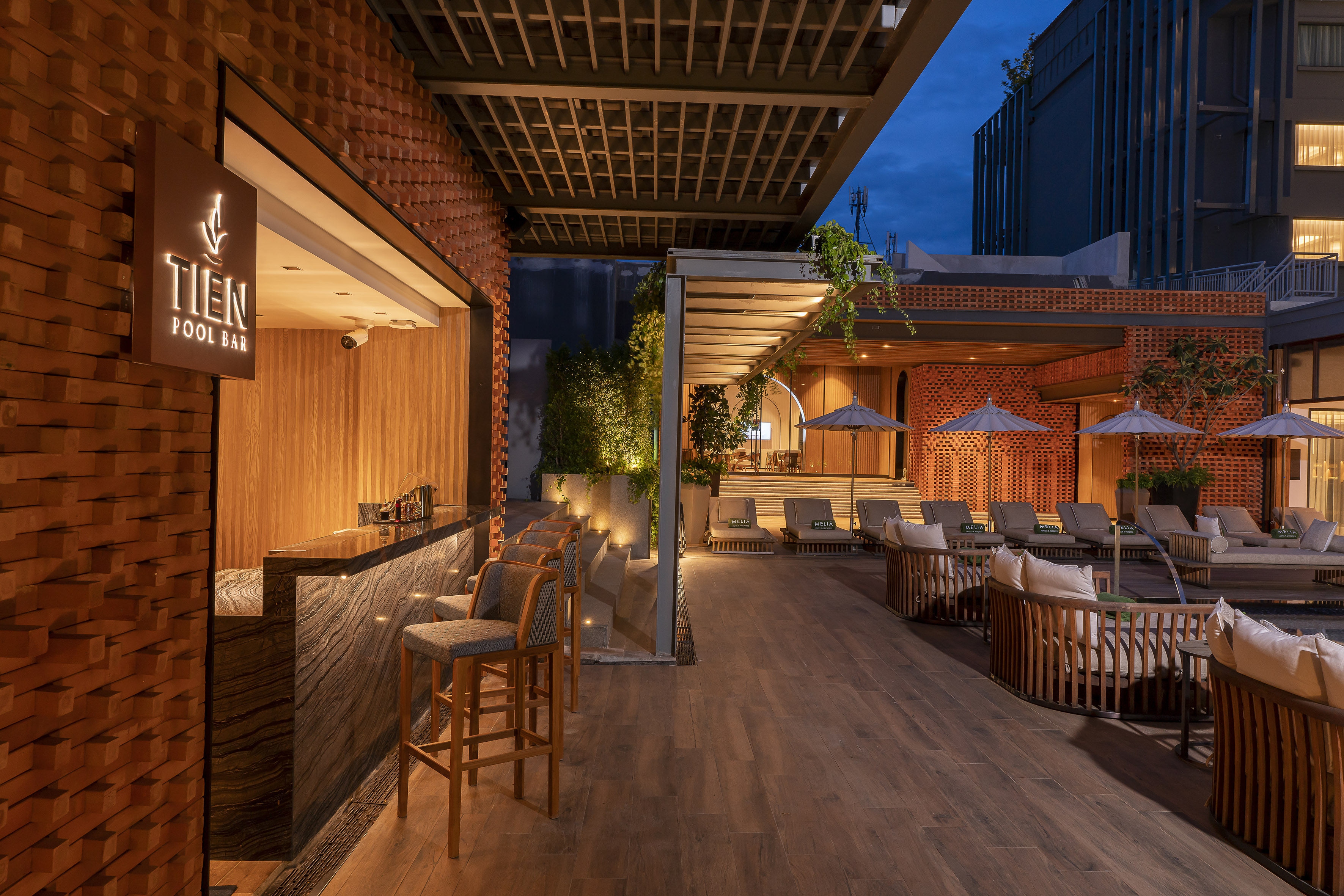Modern outdoor Tien Pool Bar, lounge seating, warm evening lights.