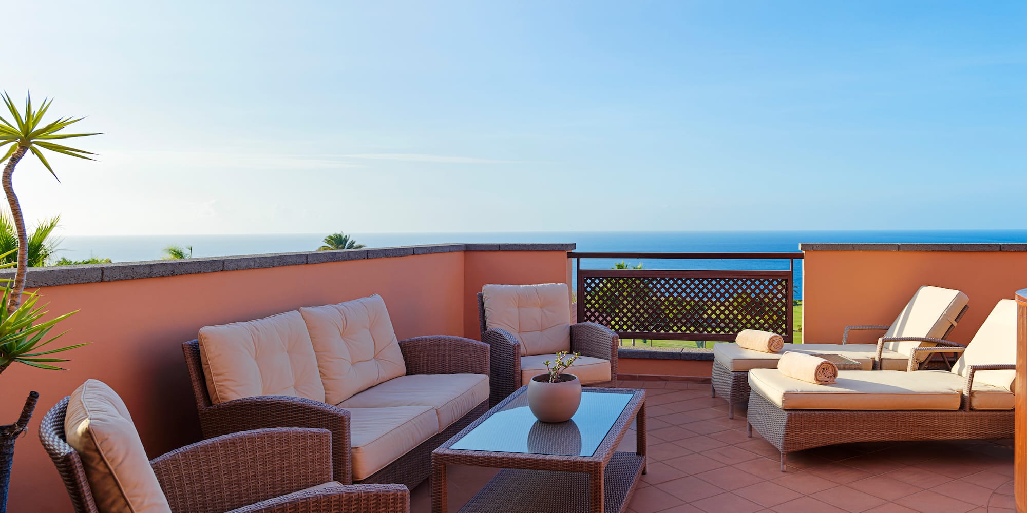 a patio with furniture on a balcony overlooking the ocean