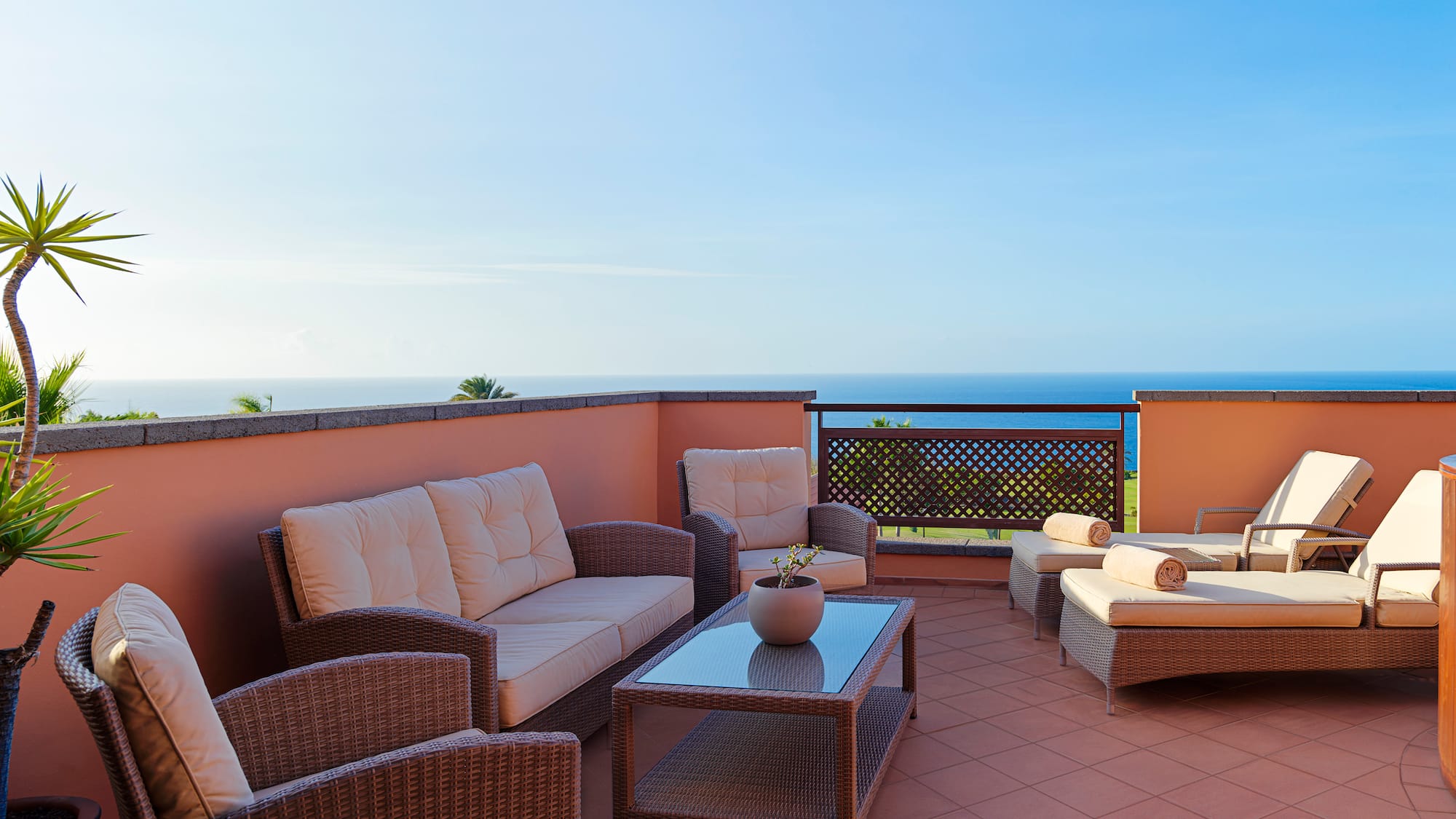a patio with furniture on a balcony overlooking the ocean
