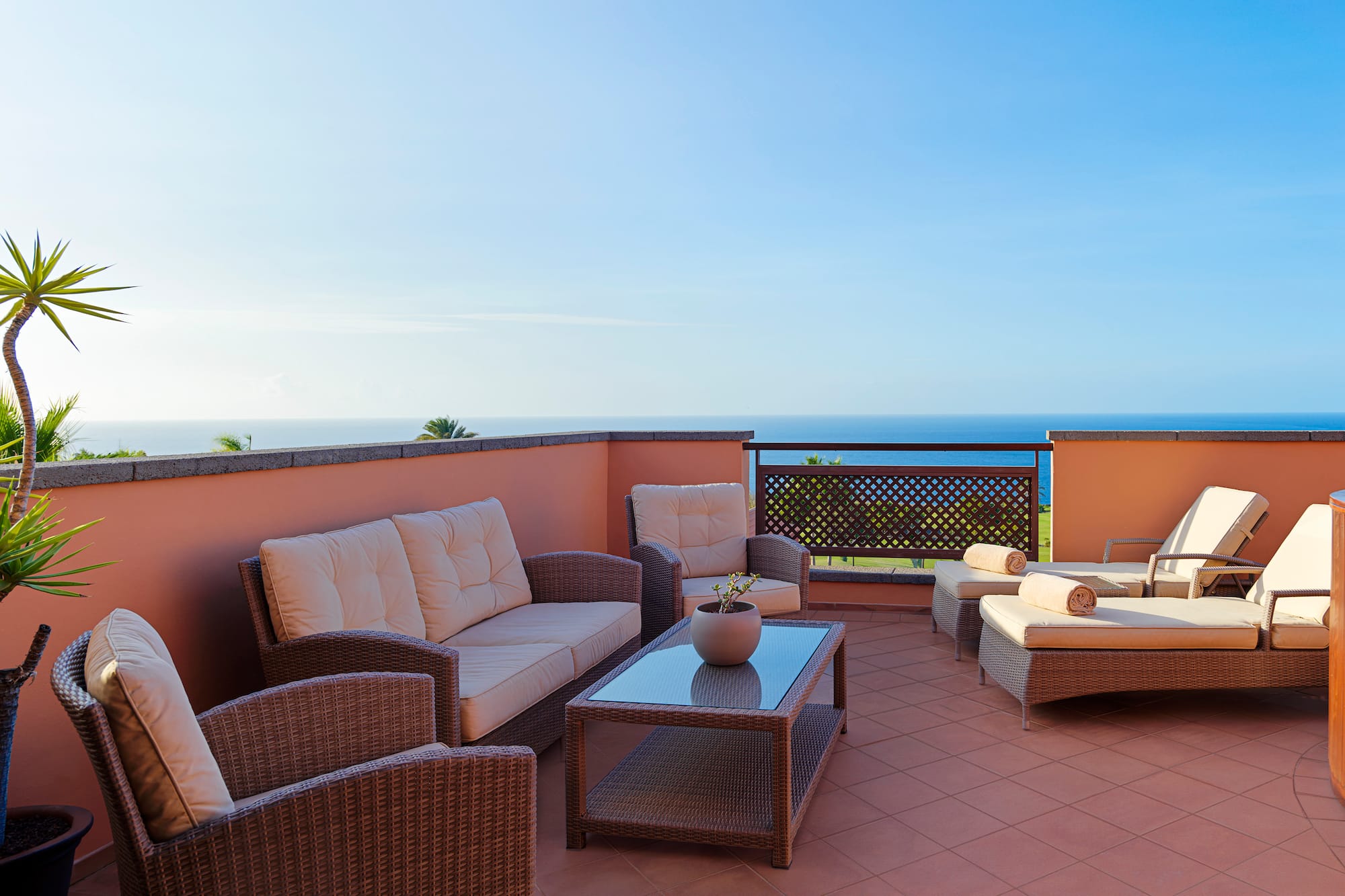 a patio with furniture on a balcony overlooking the ocean