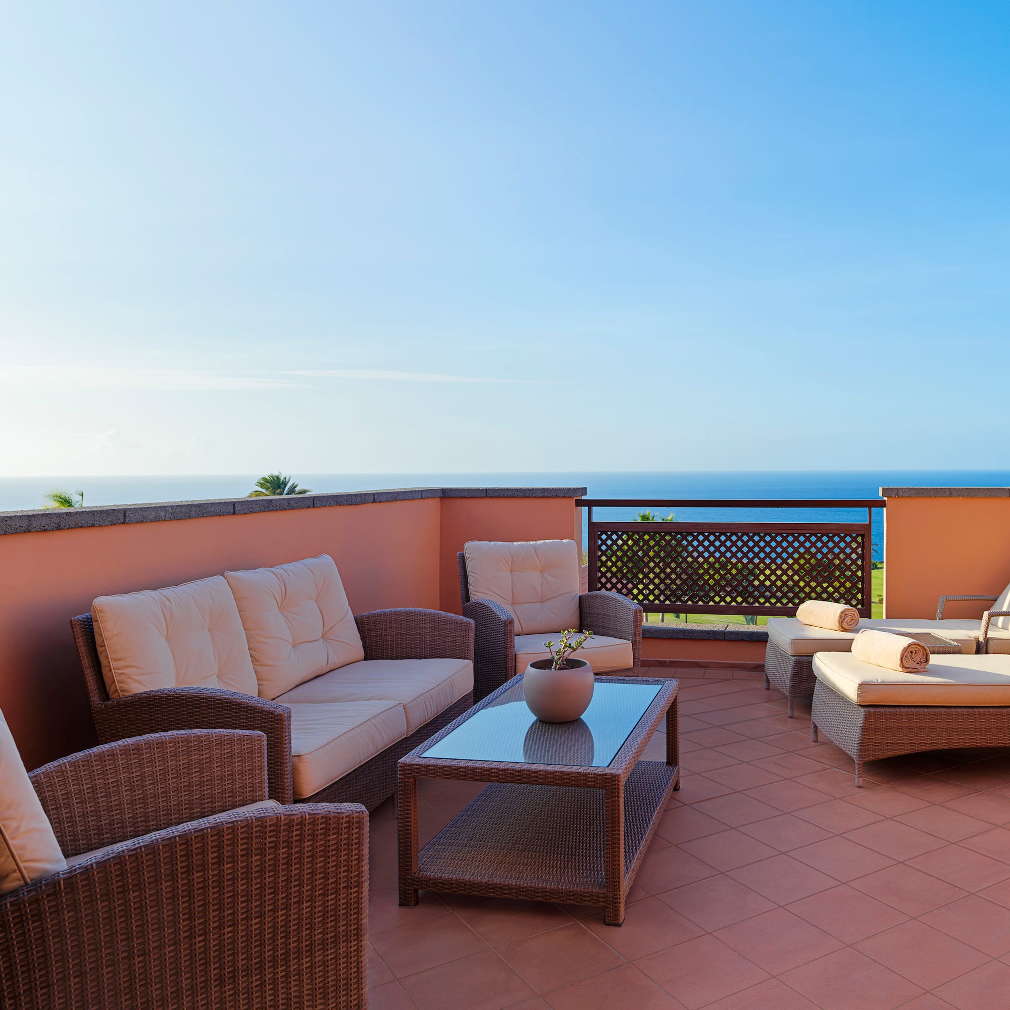 a patio with furniture on a balcony overlooking the ocean