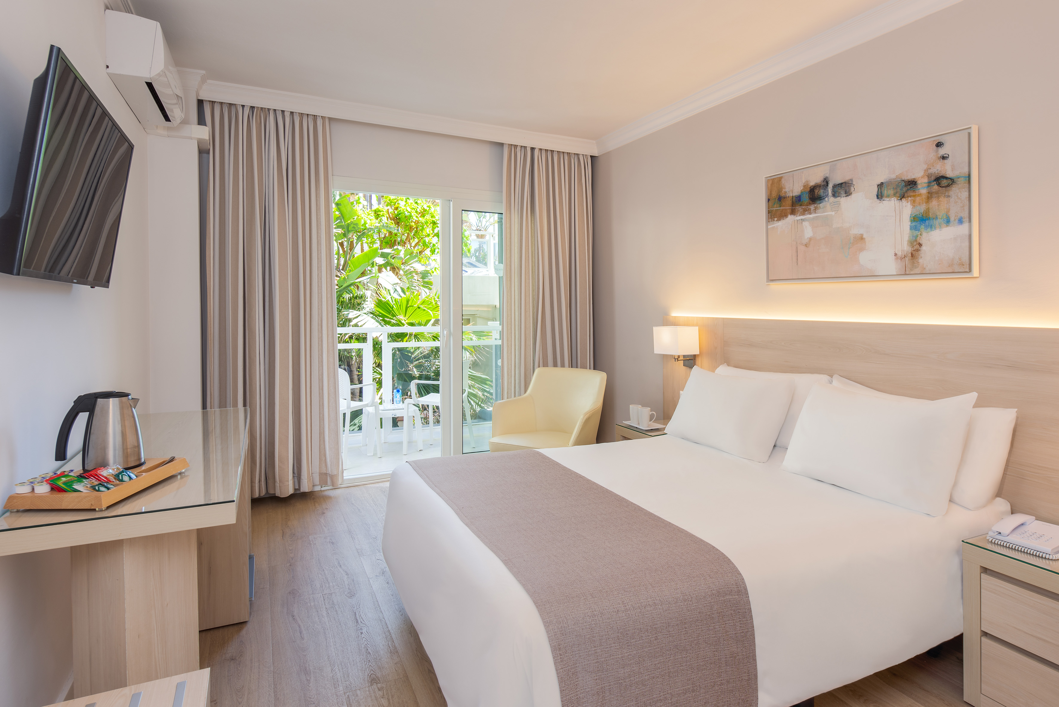 Modern hotel bedroom with bed, balcony view, TV, and stylish decor.