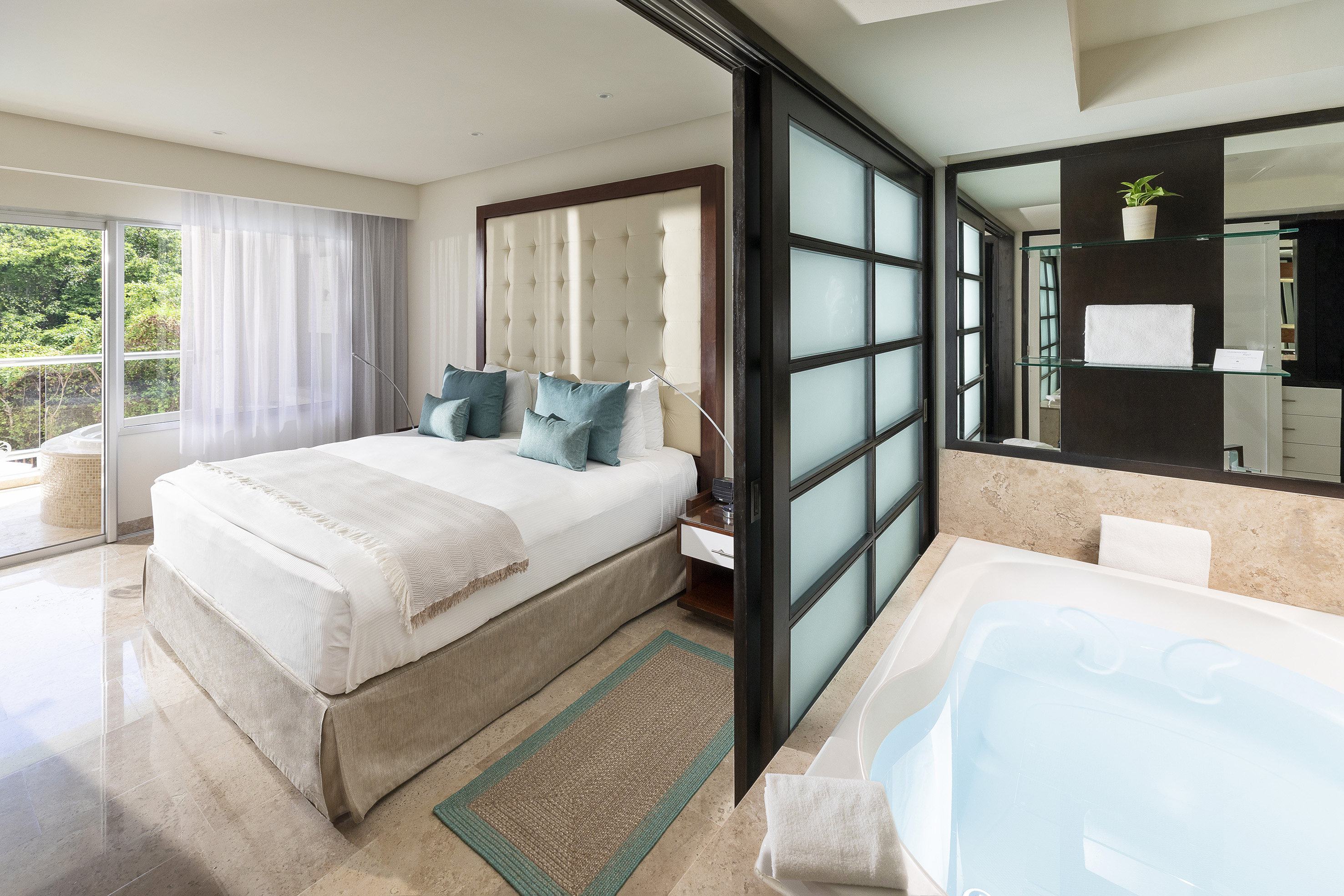 Luxury hotel suite with king bed, balcony, and adjacent jacuzzi.