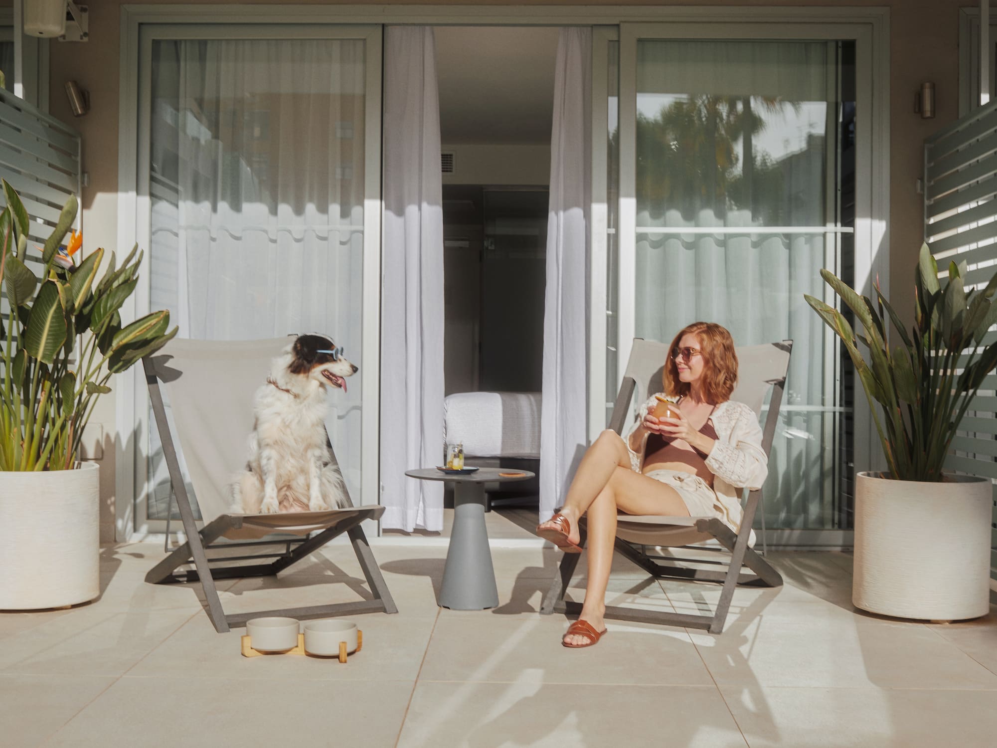 a woman and dog sitting in chairs on a patio