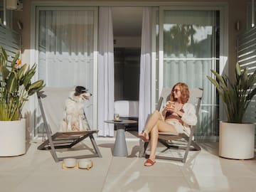 a woman and dog sitting in chairs on a patio