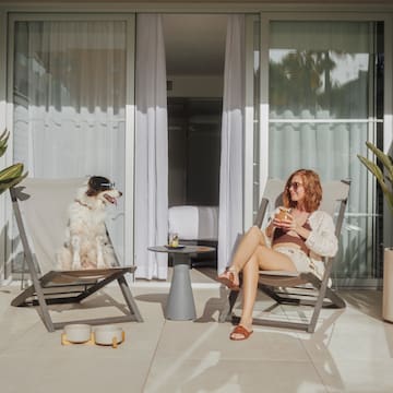 a woman and dog sitting in chairs on a patio