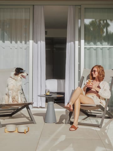 a woman and dog sitting in chairs on a patio