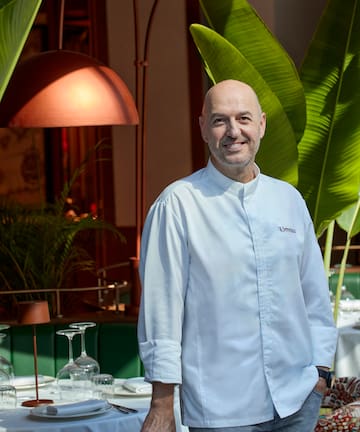 a man standing in front of a table with glasses and a table with a lamp