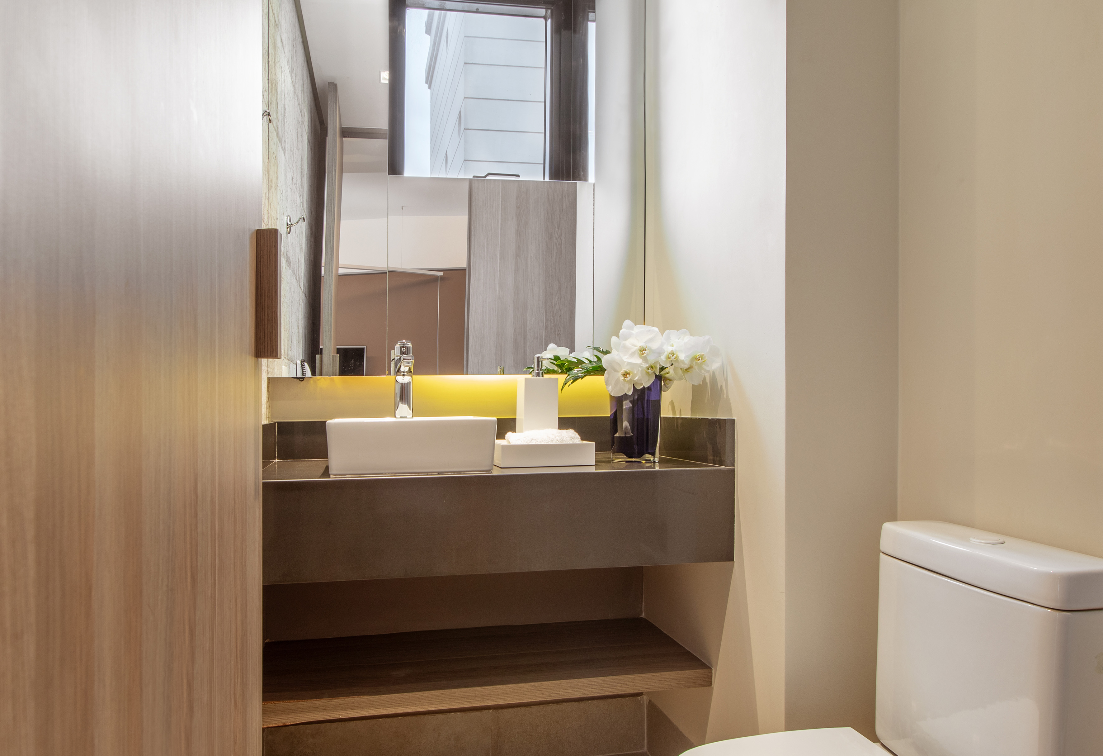 Modern bathroom vanity with vessel sink, chrome faucet, and white orchids.