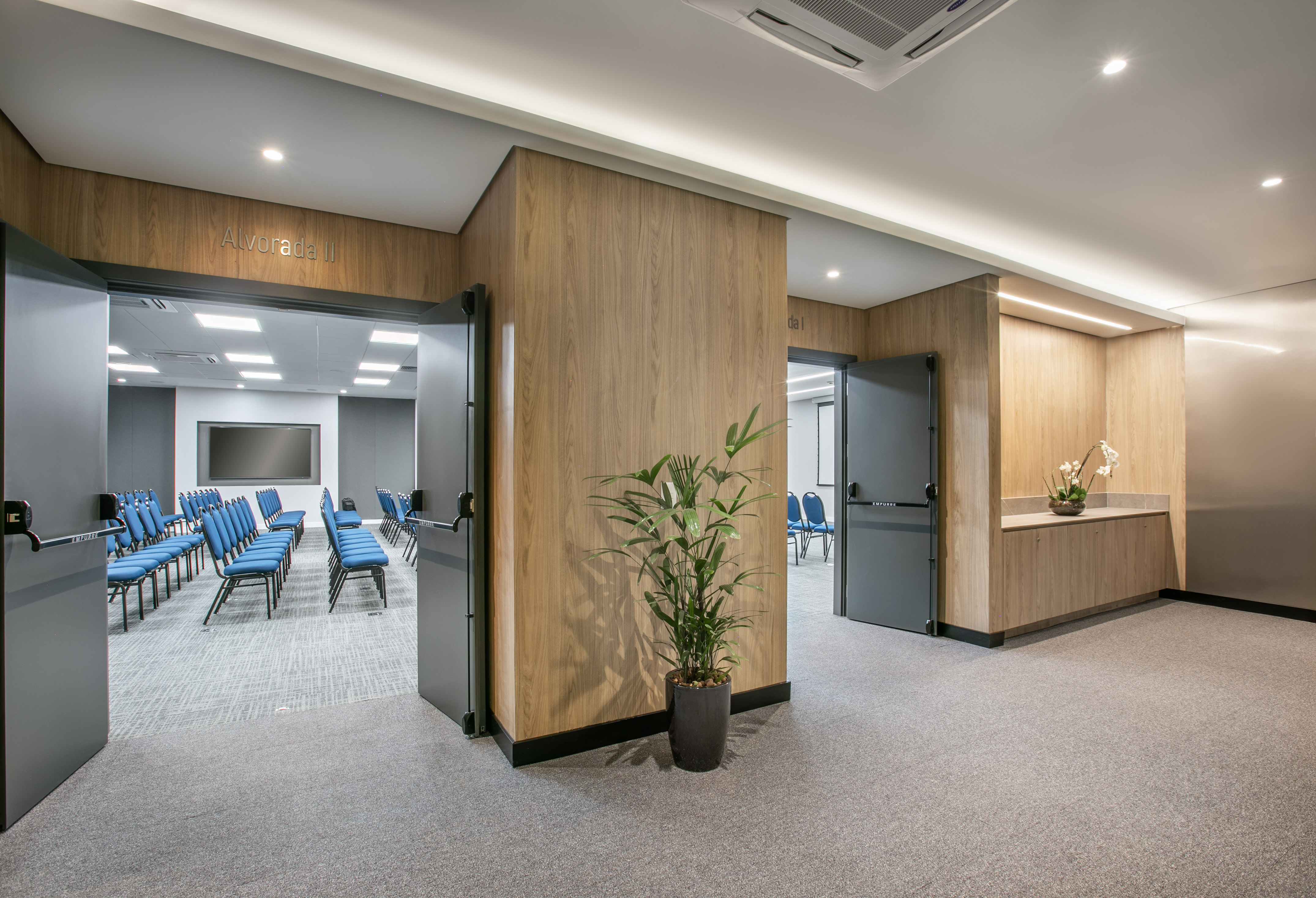 Modern conference room entrance with blue chairs, screen, and wood paneling.