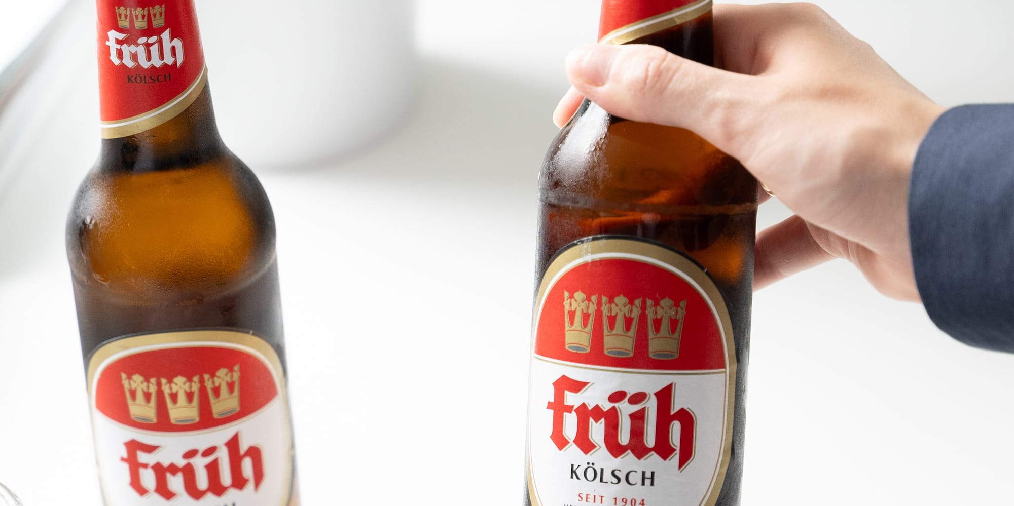 a hand holding a bottle of beer