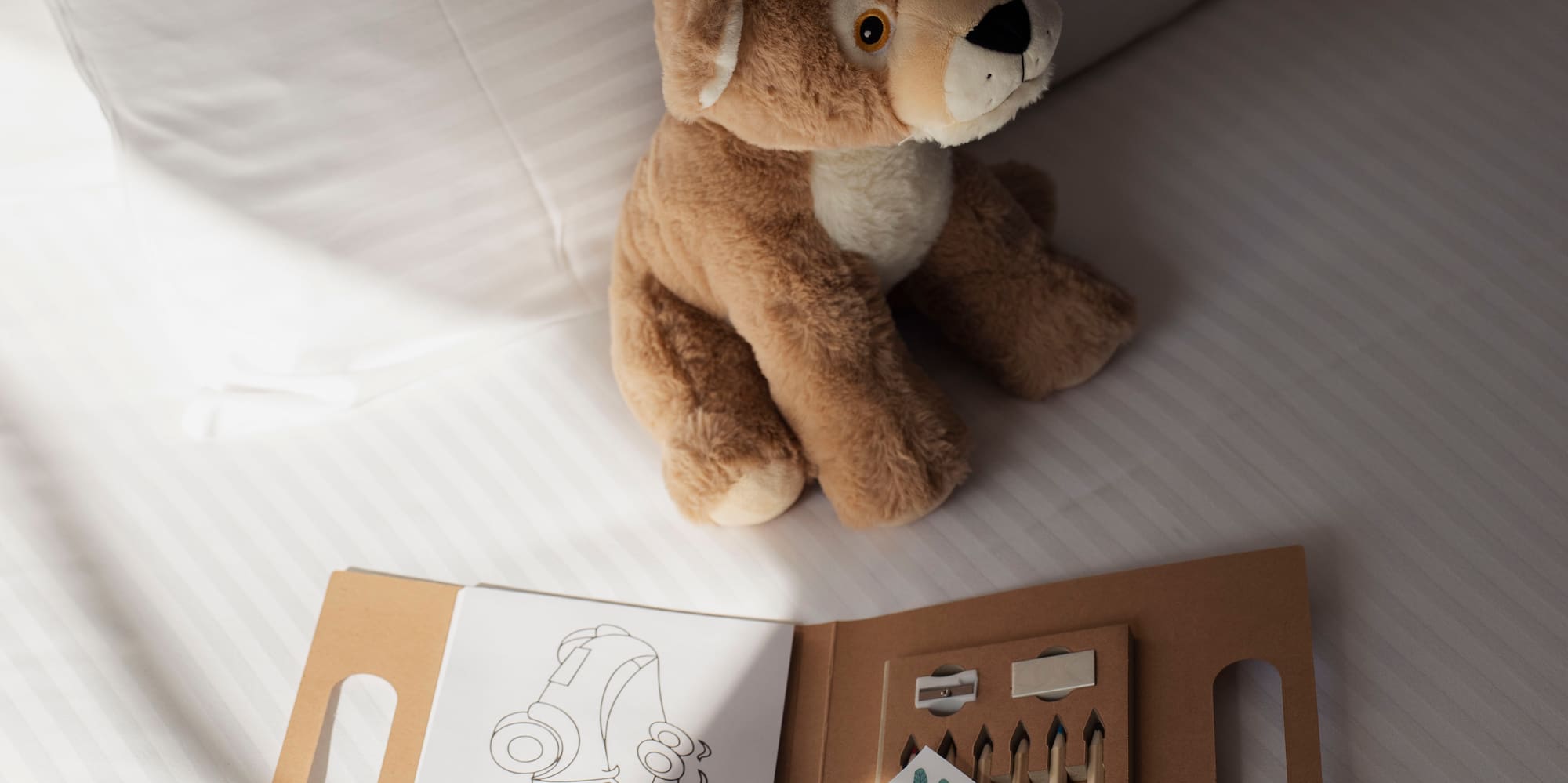 New baby welcome gift with plush lion, coloring book on hotel bed.