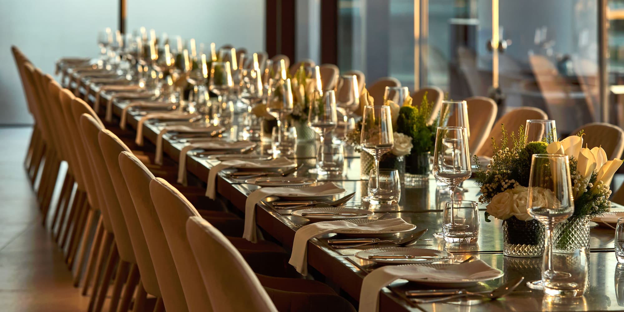 a long table with glasses and flowers