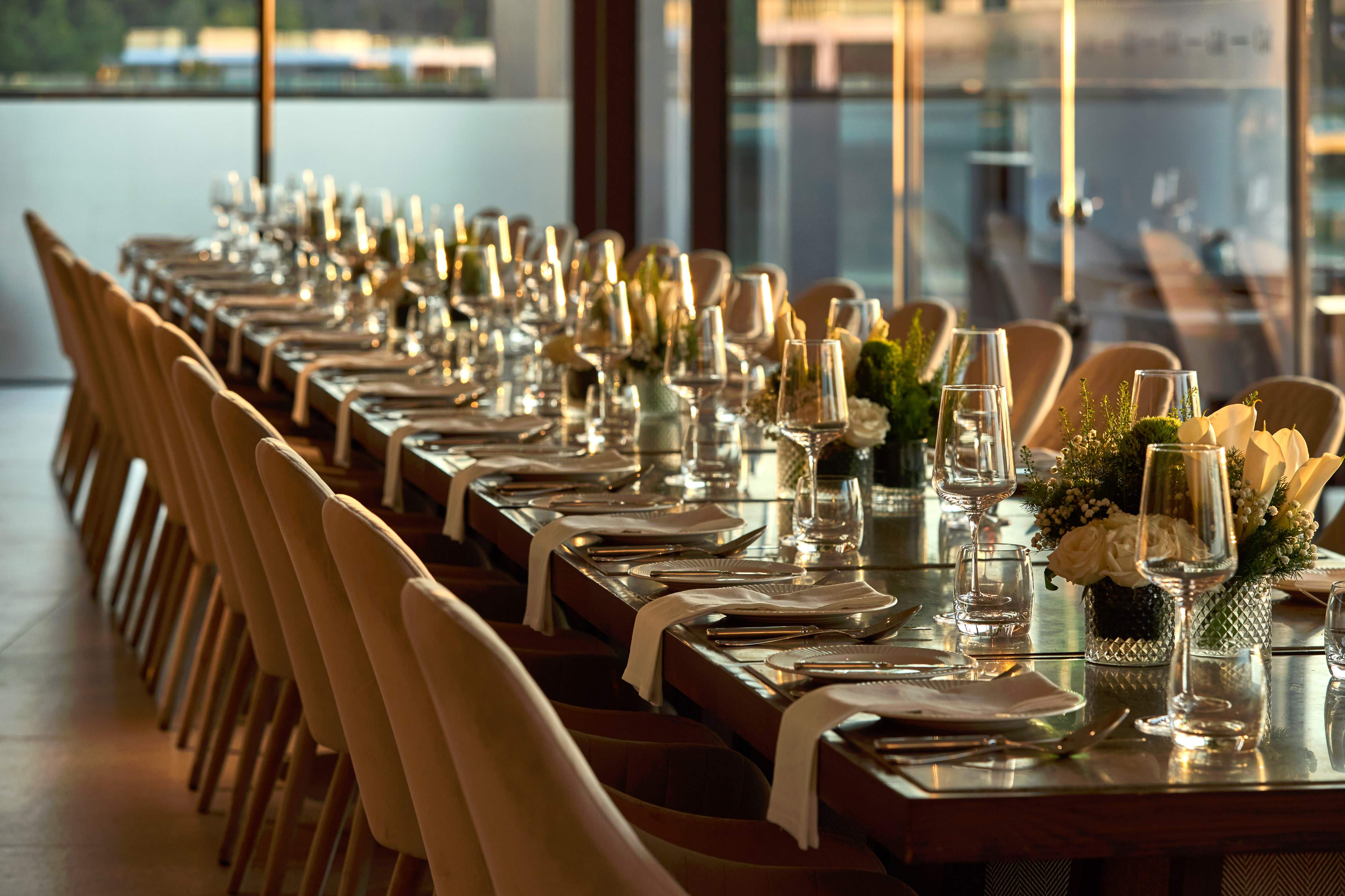 Elegant dining table set with place settings, wine glasses, and floral decor.