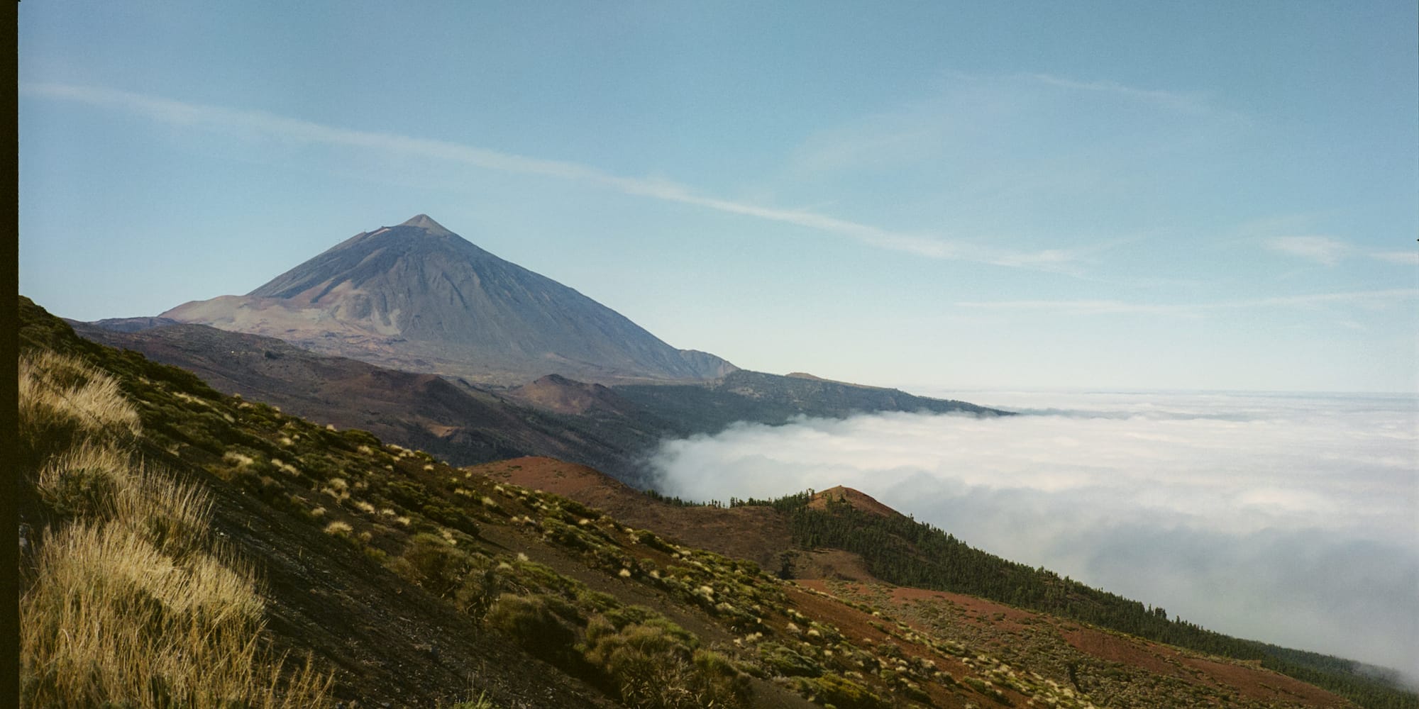 a mountain with a hill and clouds in the background