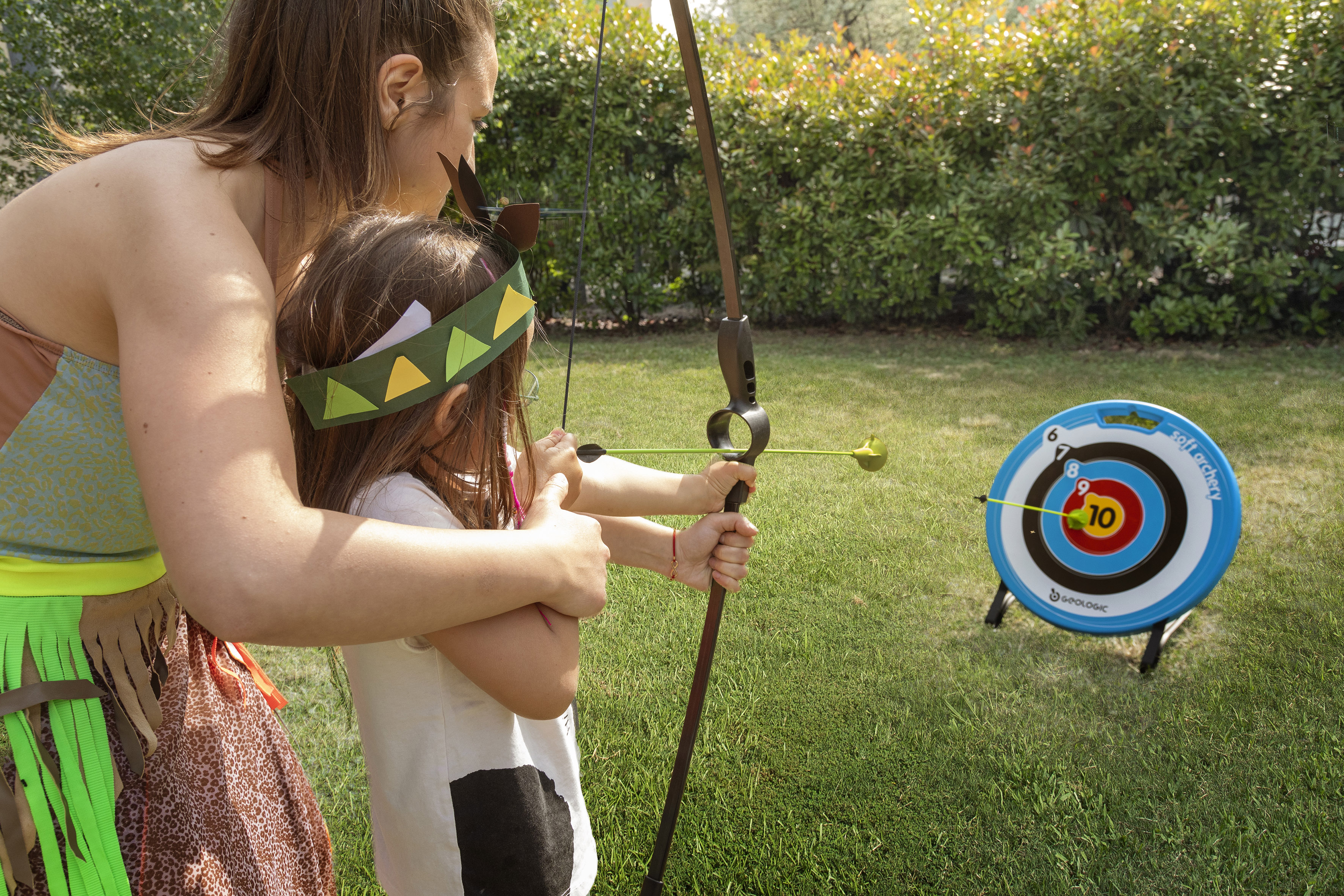 a woman and a girl shooting a bow and arrow