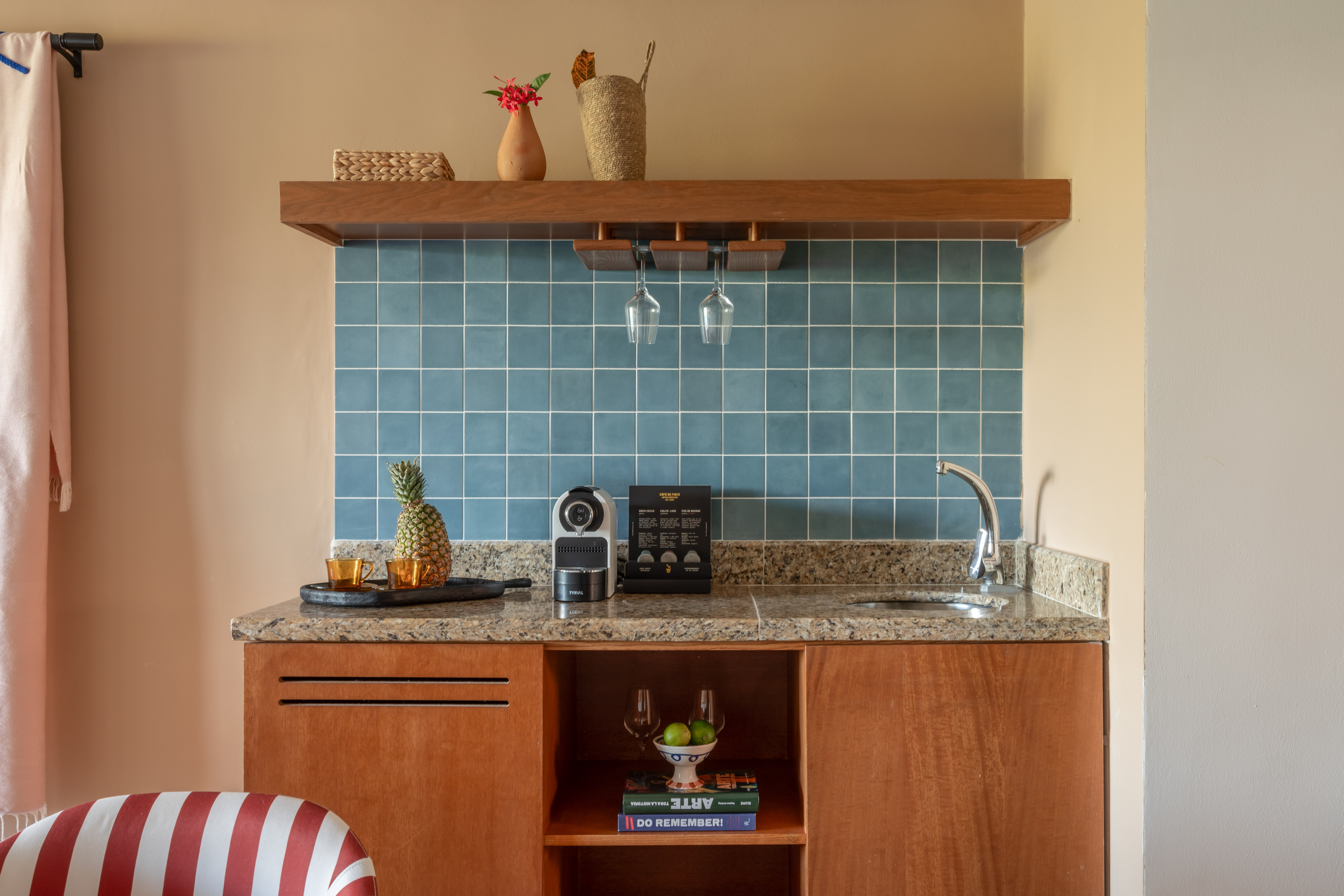 Stylish mini-bar with blue tiles, coffee machine, pineapple, and wood cabinets.
