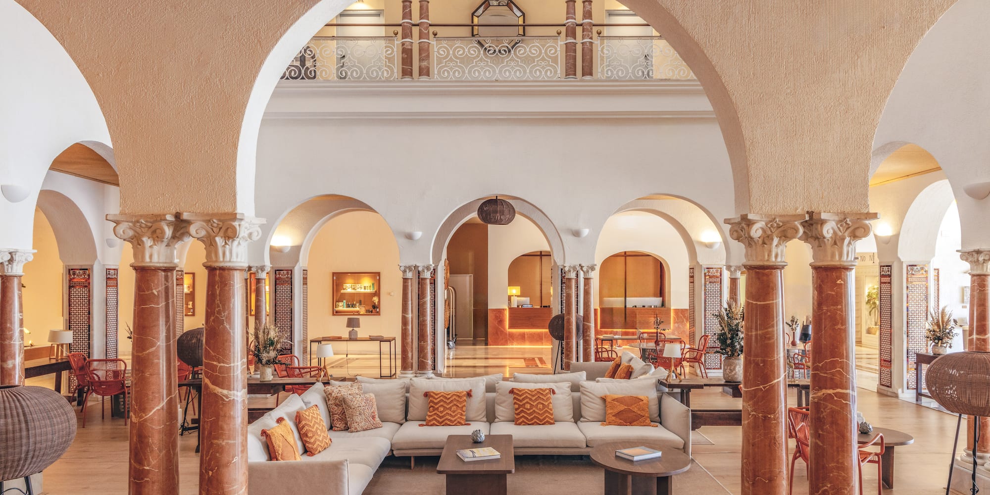Elegant hotel lobby with arches, ornate columns, comfortable seating, and reception.