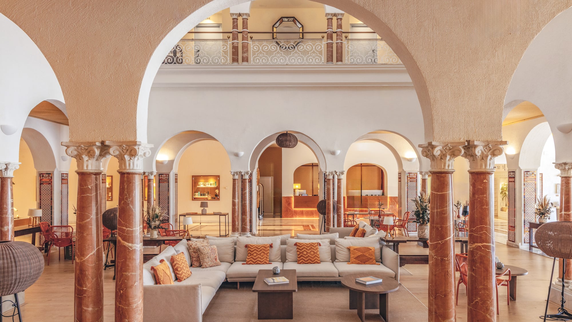 Elegant hotel lobby with arches, ornate columns, comfortable seating, and reception.