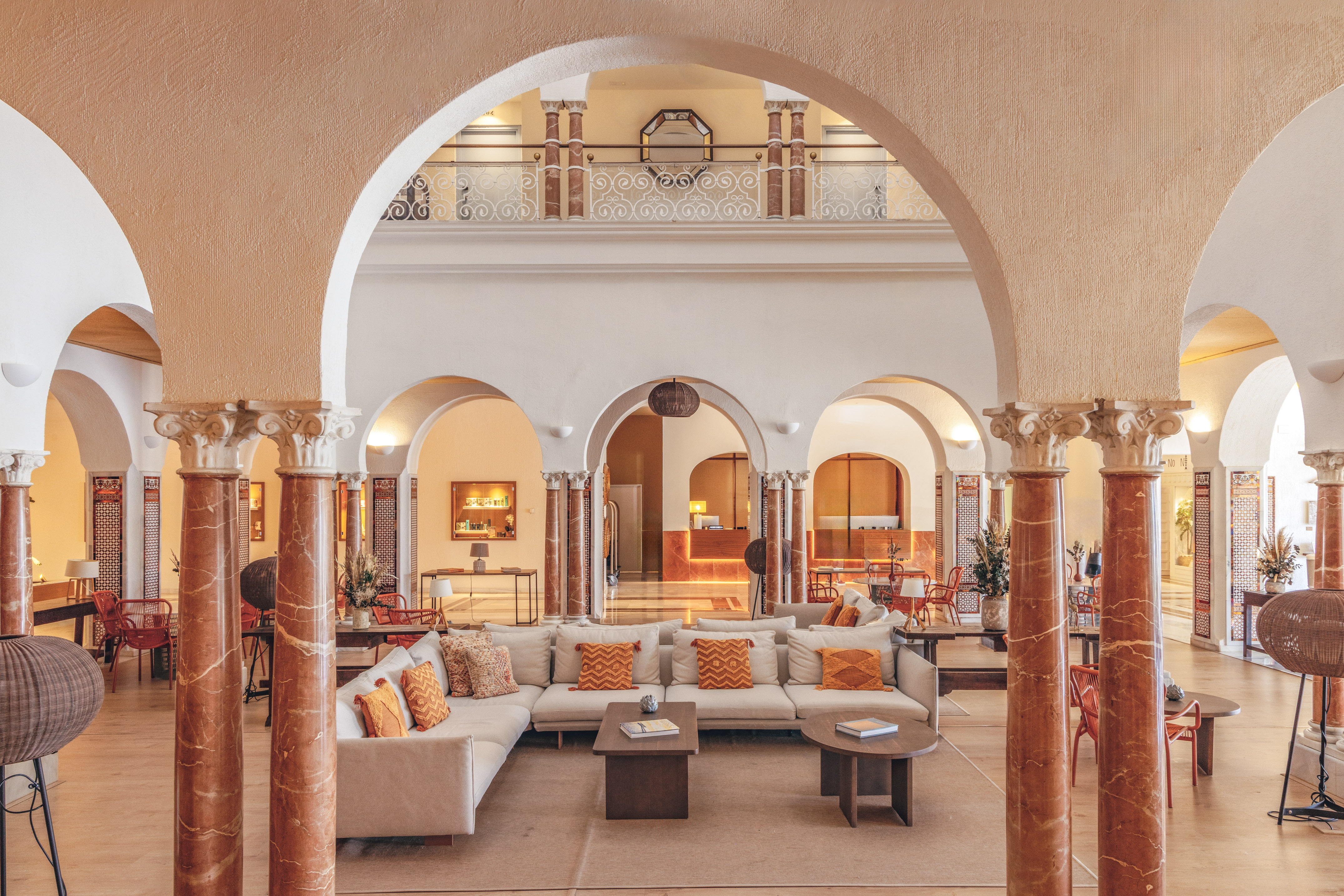Elegant hotel lobby with arches, ornate columns, comfortable seating, and reception.