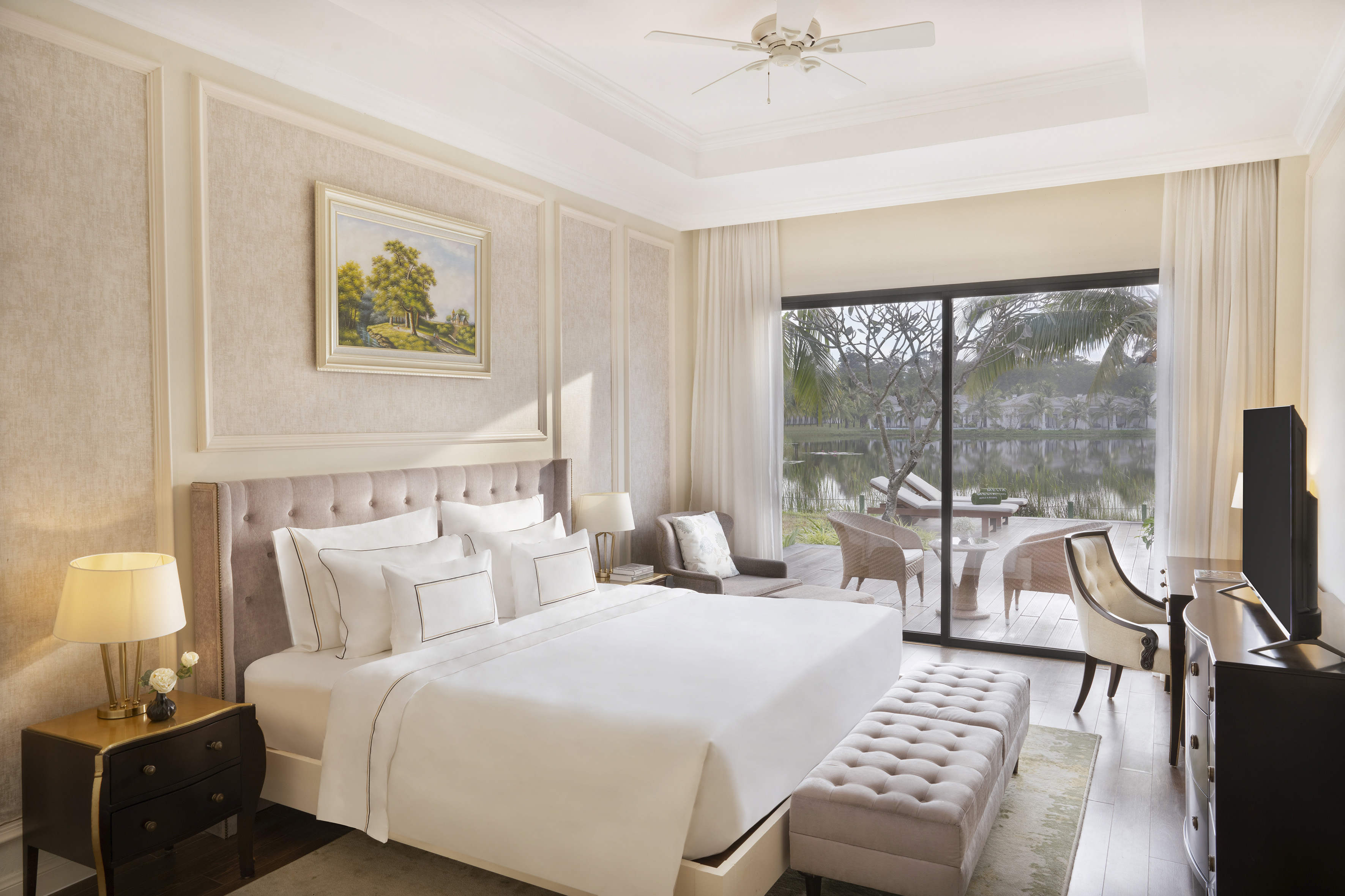 Luxury hotel bedroom suite with lake view balcony, king bed, and elegant decor.
