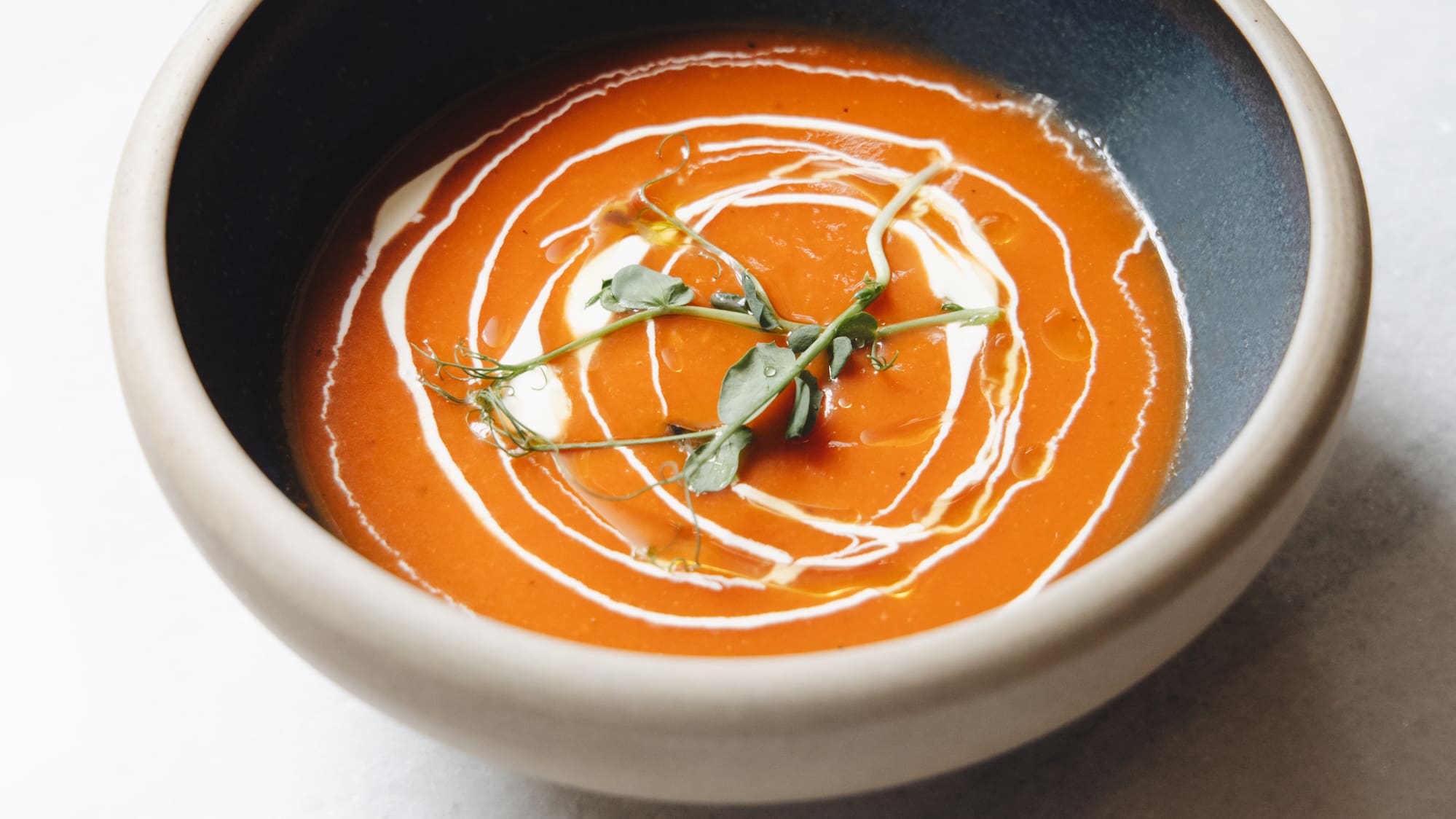 a bowl of soup with a leafy green sprig in it