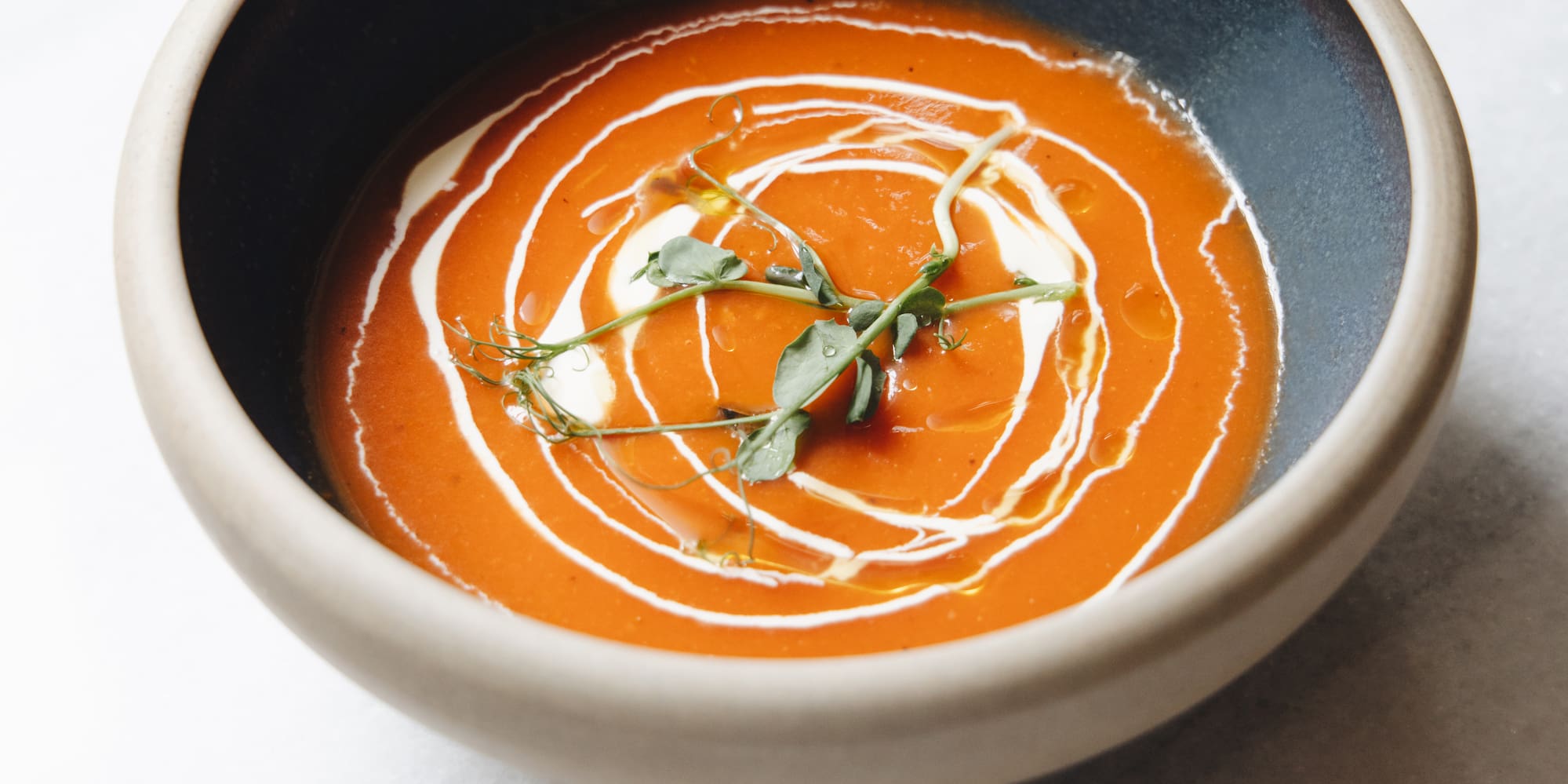 a bowl of soup with a leafy green sprig in it