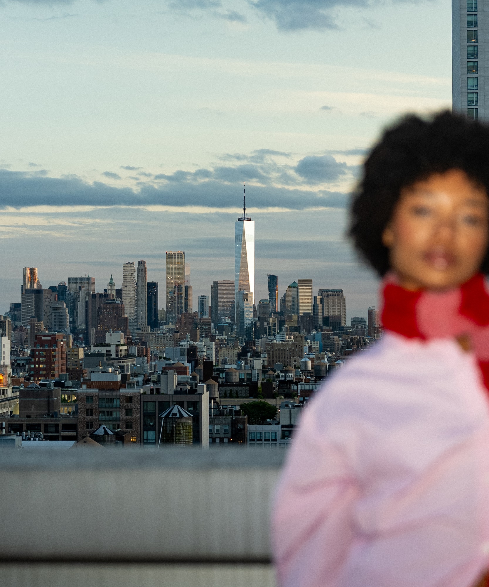 a woman standing on a rooftop with a city in the background