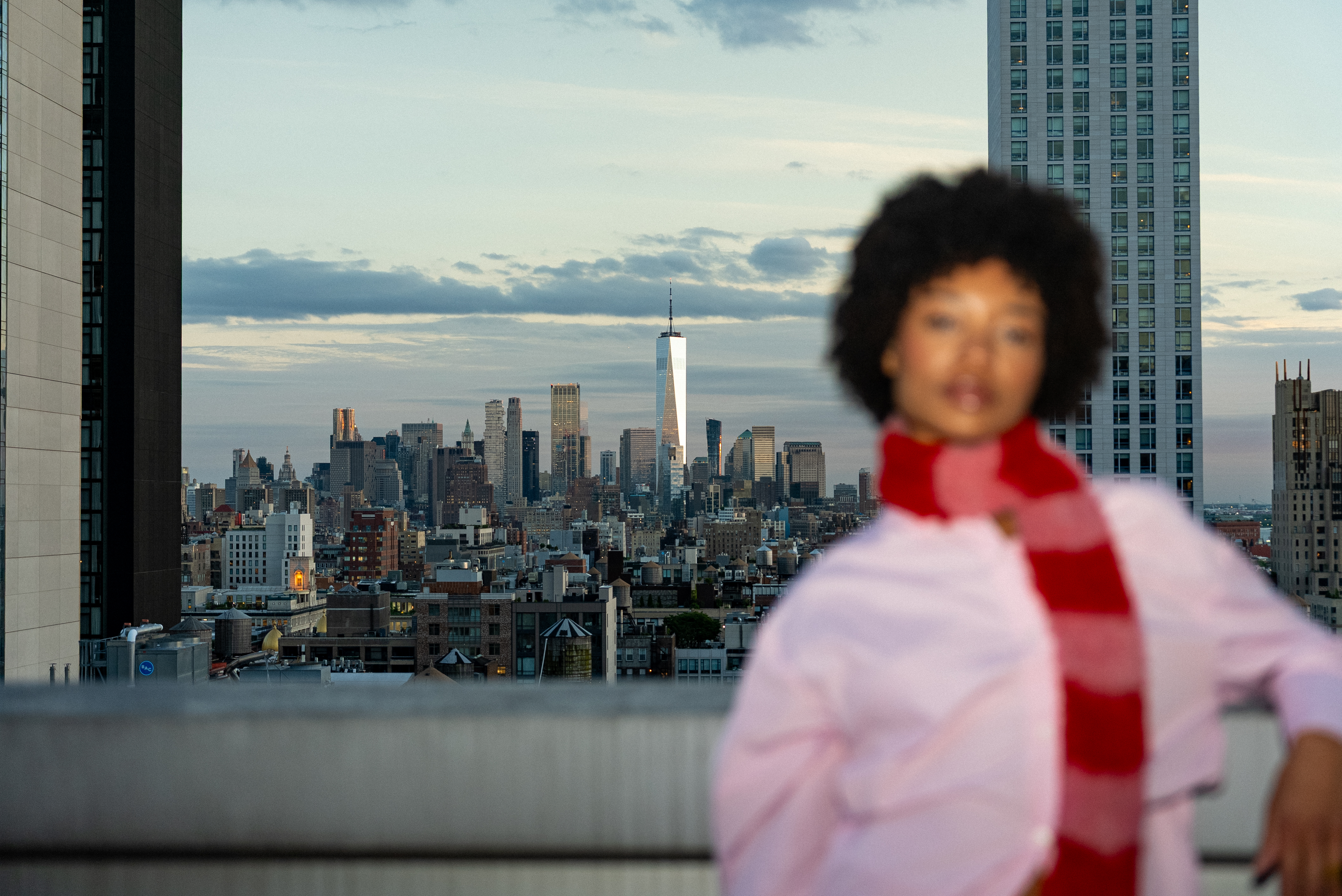 New York City skyline with One World Trade Center, blurred woman, red scarf.