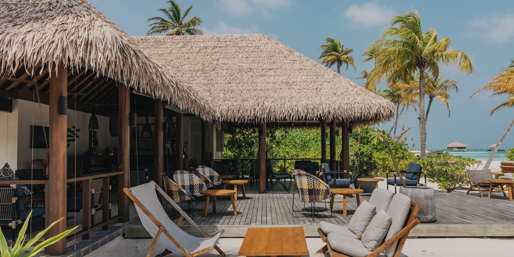 a deck with chairs and a table on a beach