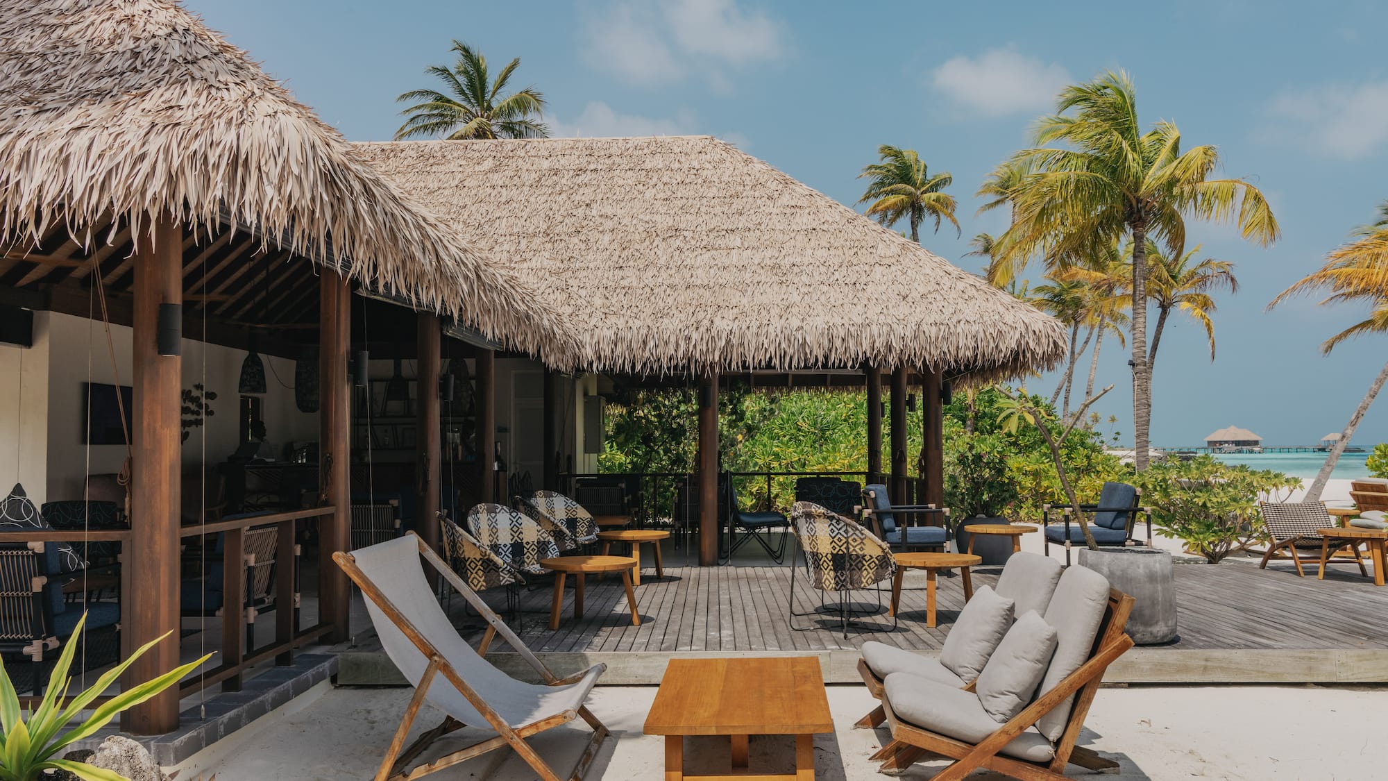 a deck with chairs and a table on a beach