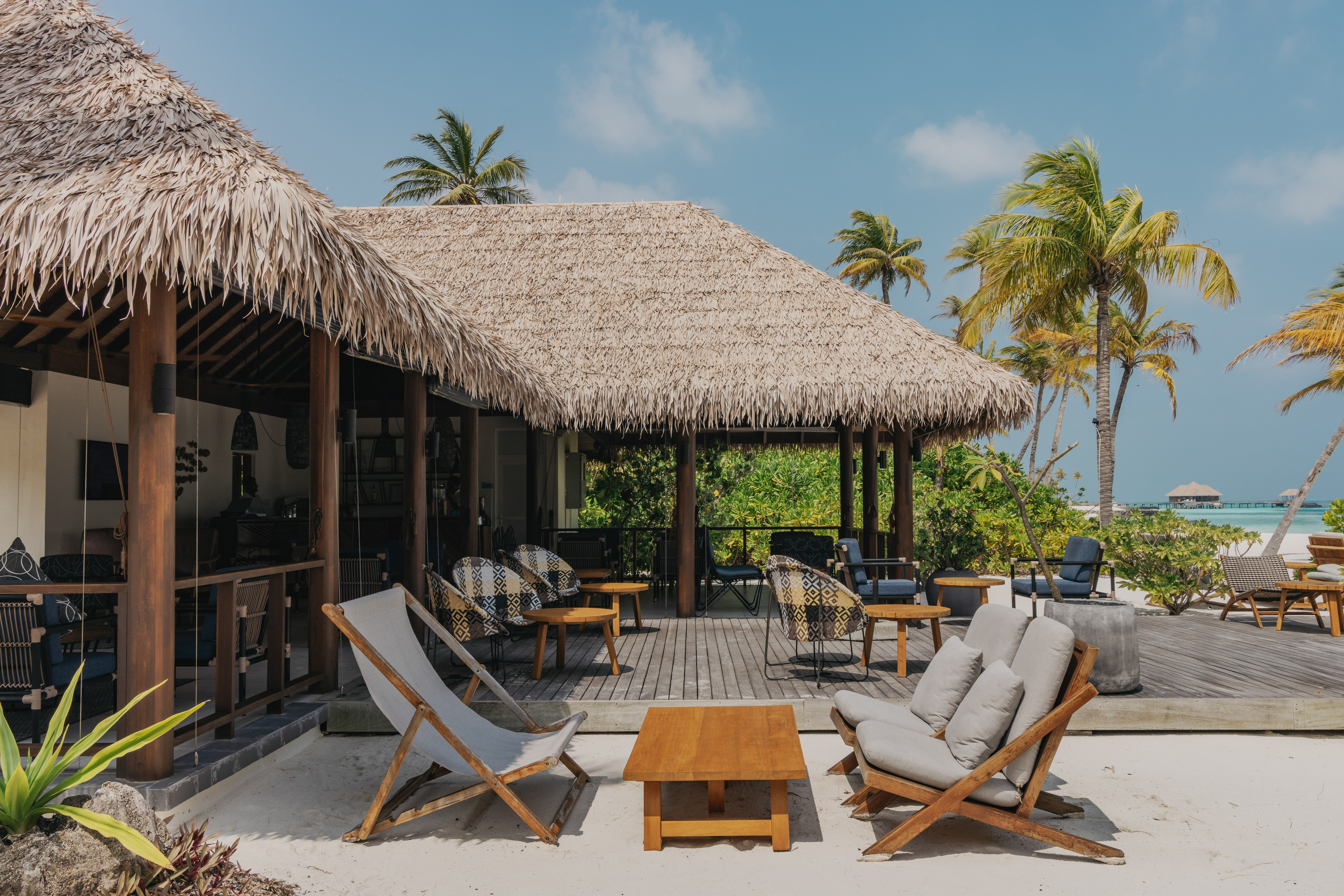 a deck with chairs and a table on a beach