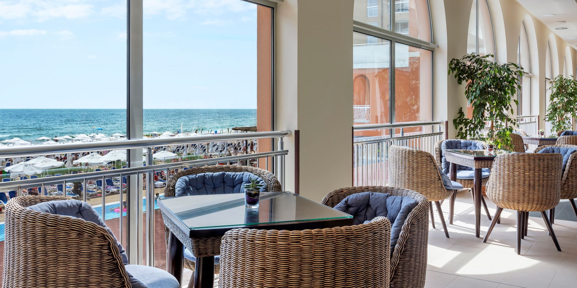 a room with a table and chairs and a balcony overlooking the ocean