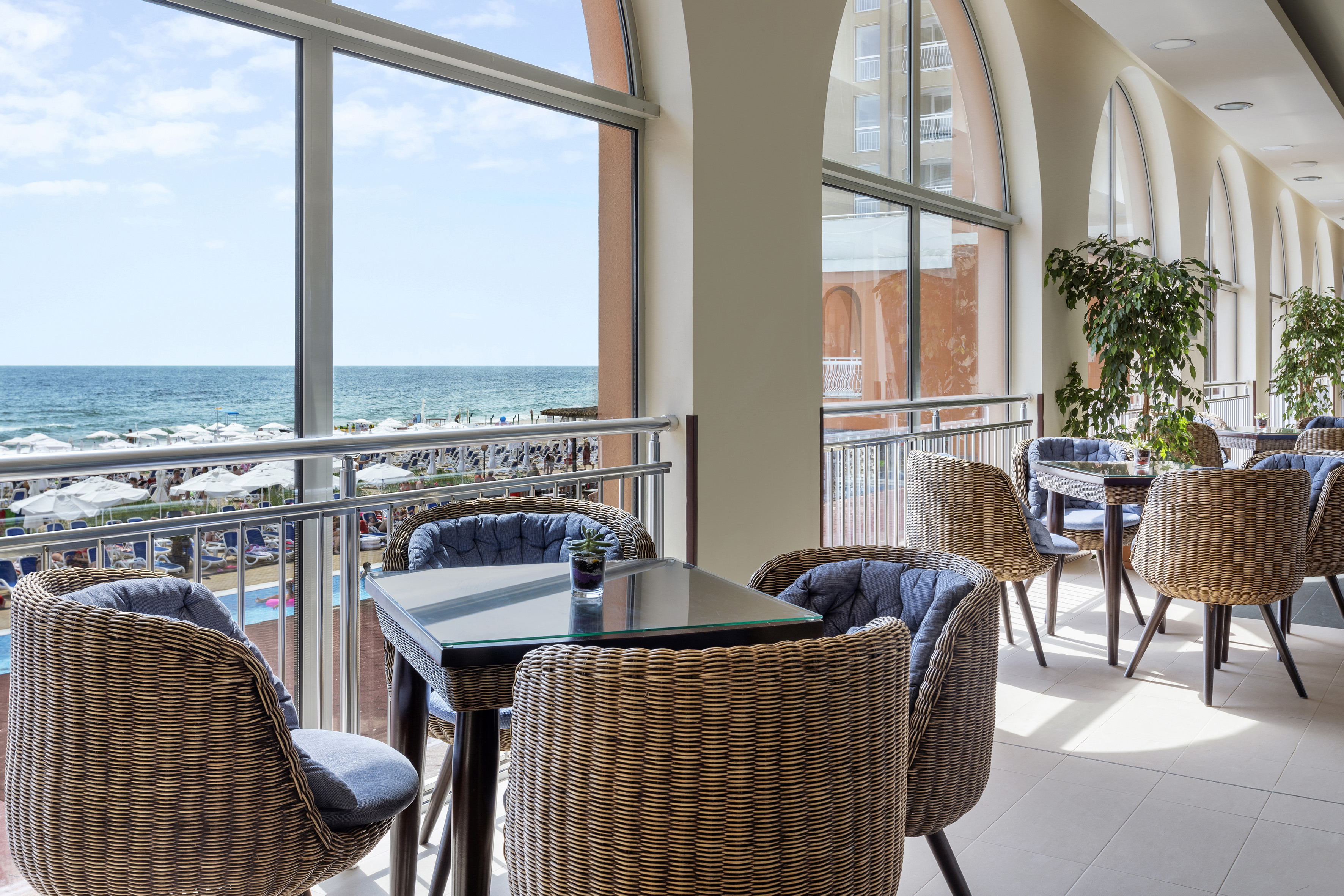a room with a table and chairs and a balcony overlooking the ocean
