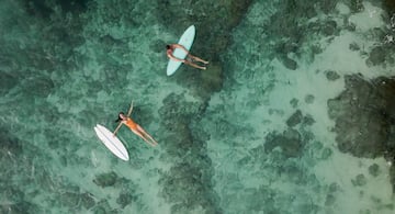 a man and woman in a swimsuit on surfboards in the water