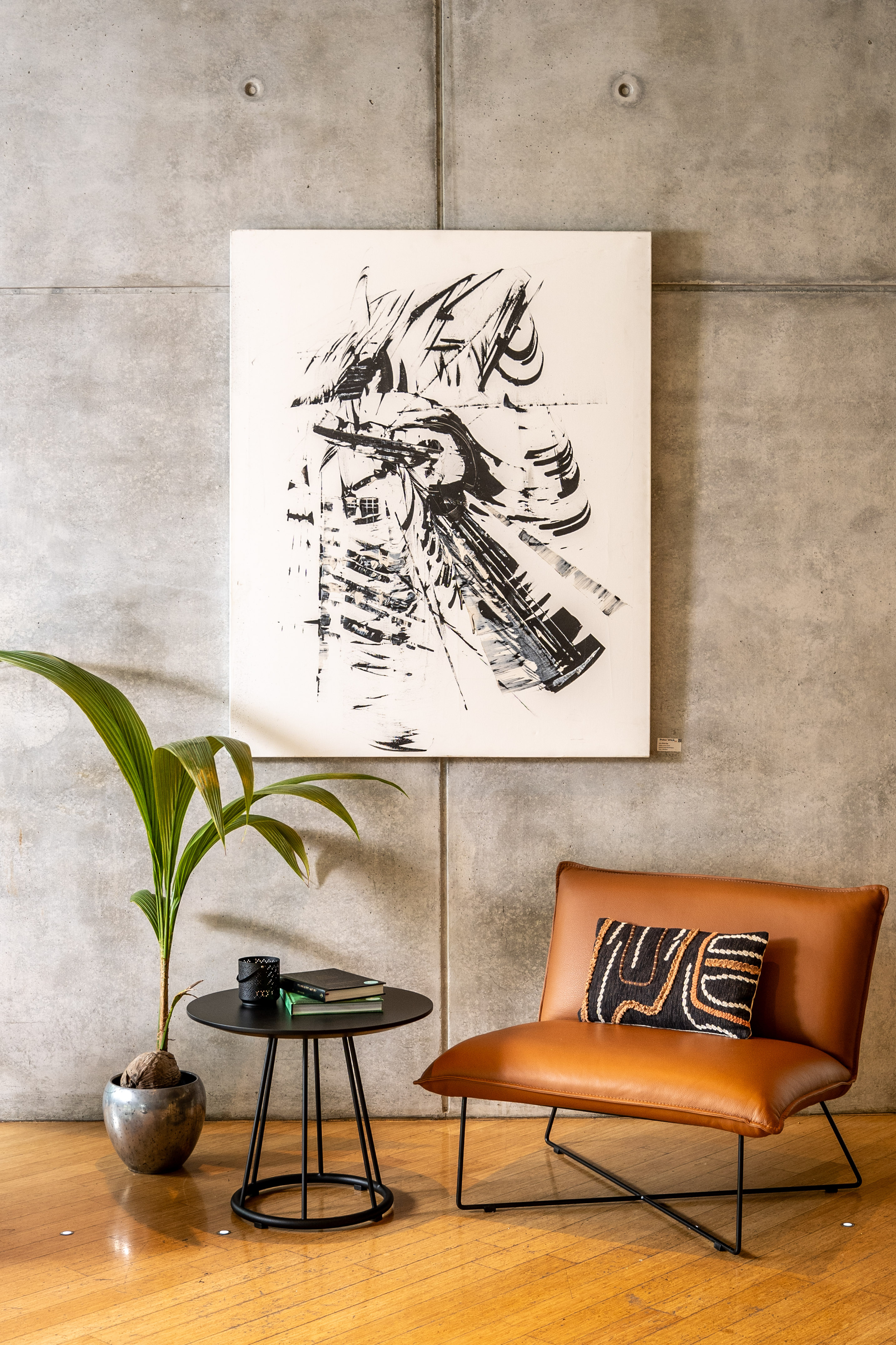 Modern industrial interior: leather lounge chair, abstract art, concrete wall.