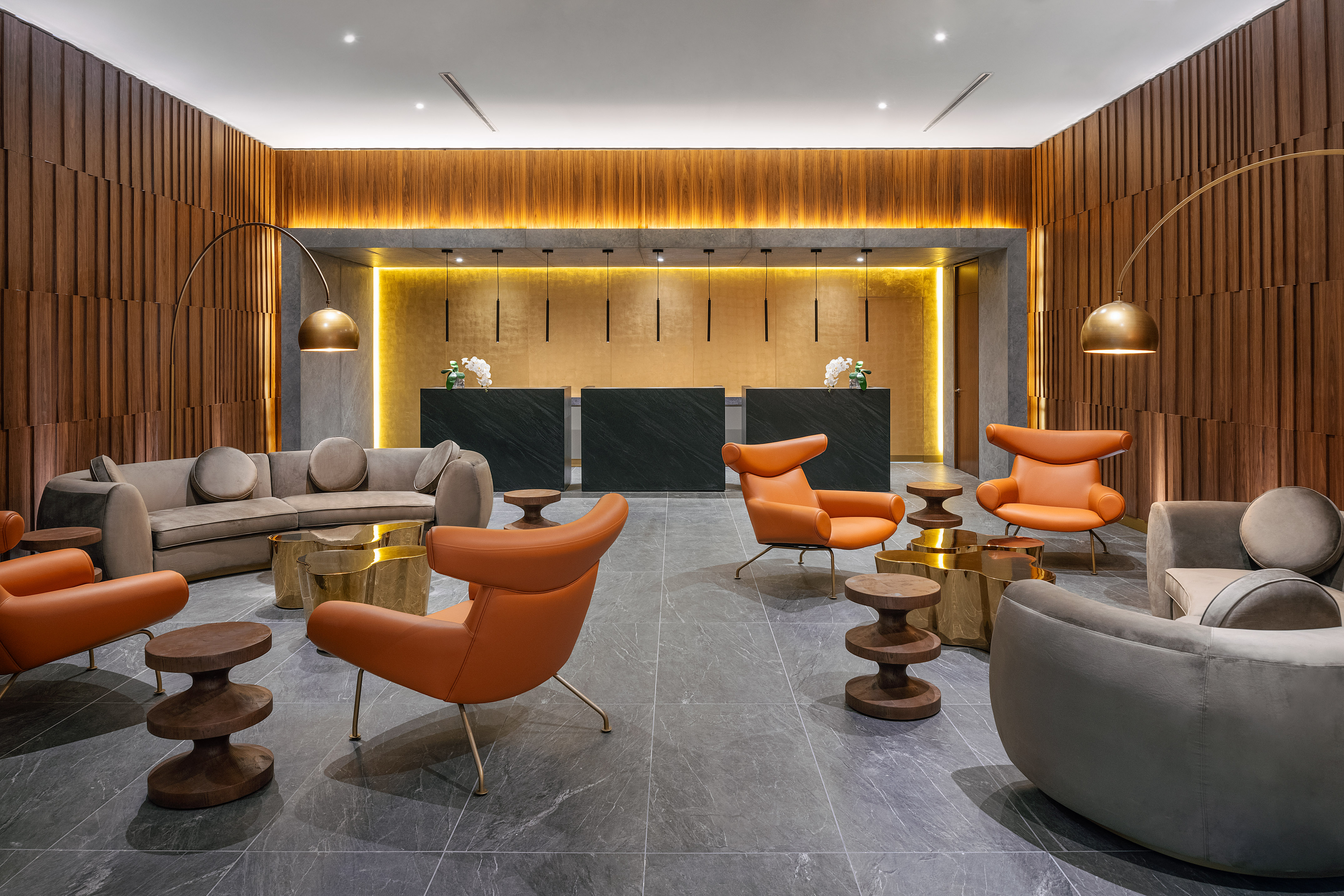 Hotel lobby with black reception desks, modern lounge chairs, and wood panels.
