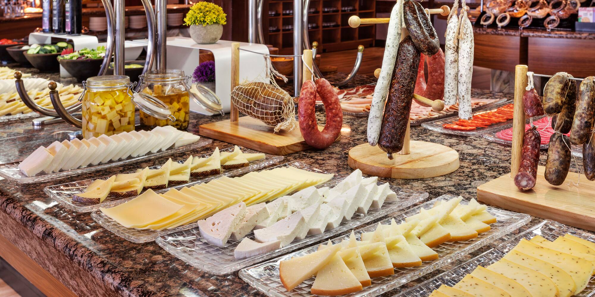 a counter with different types of cheese and sausages