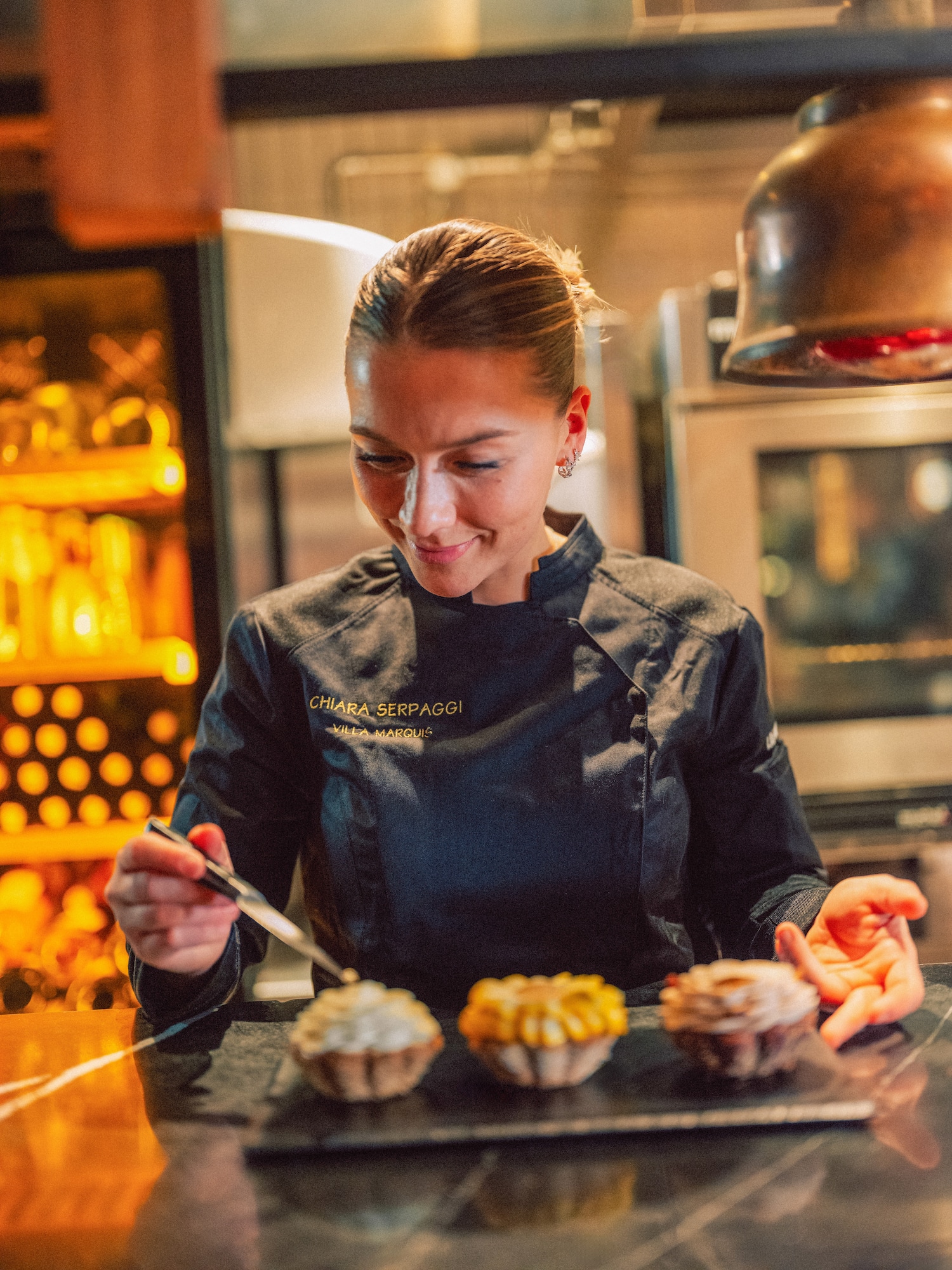 Chiara Serpaggi, Villa Marquis chef, garnishing three exquisite pastries.